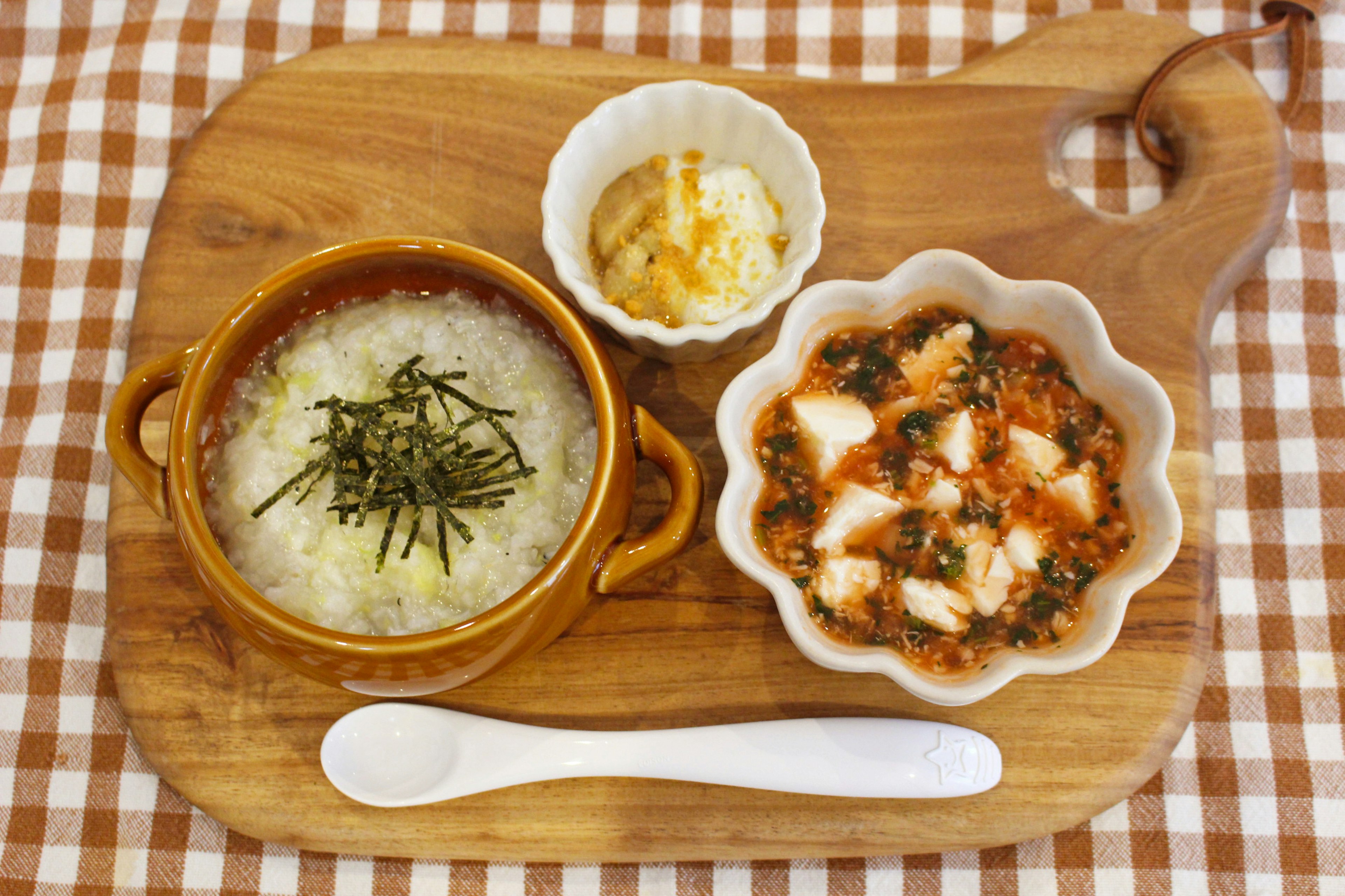 A wooden tray featuring porridge and side dishes