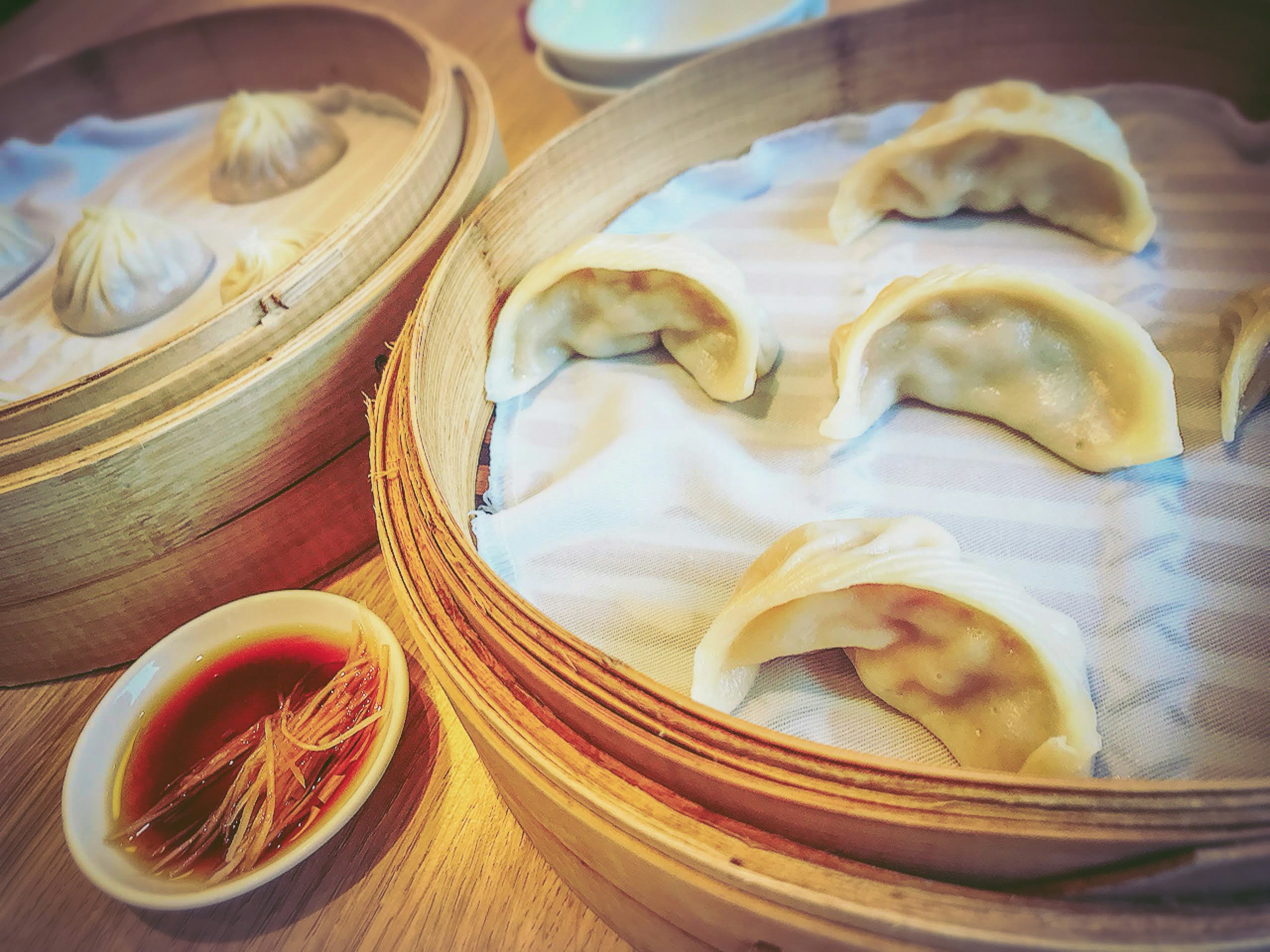 Steamed dumplings in a bamboo steamer with dipping sauce