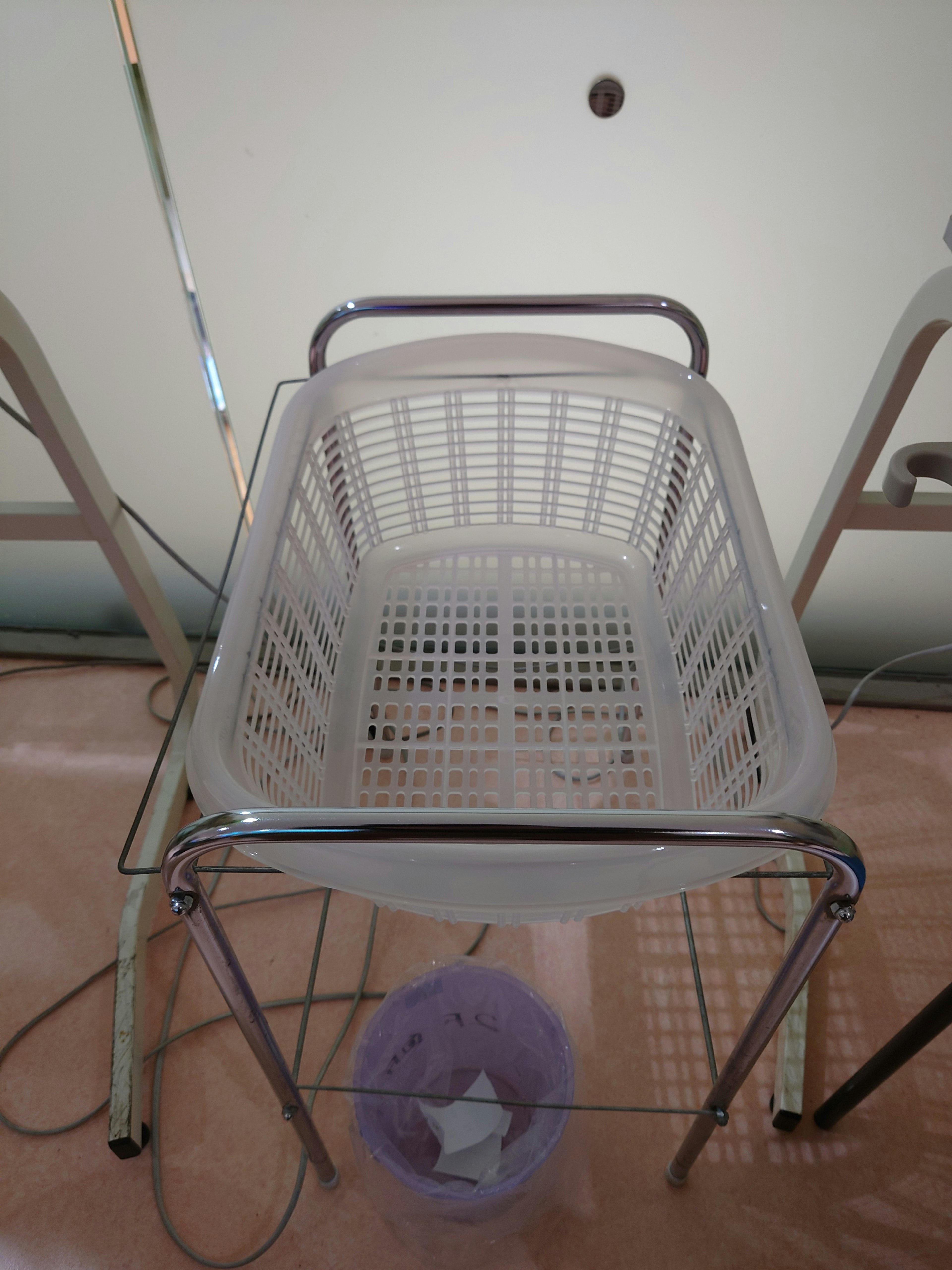 Image of a white plastic basket placed on a metal frame