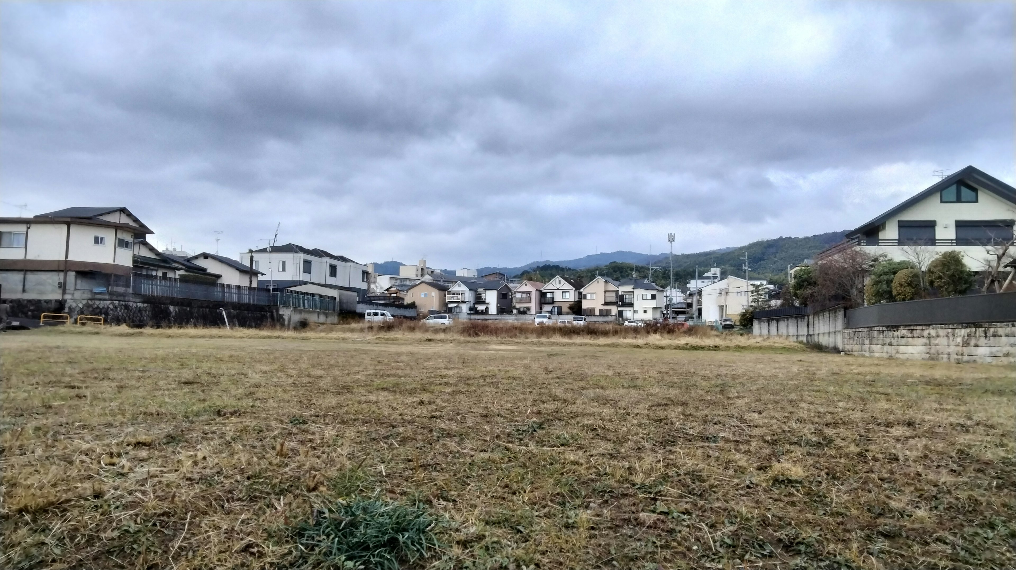 Open field with residential buildings in the background