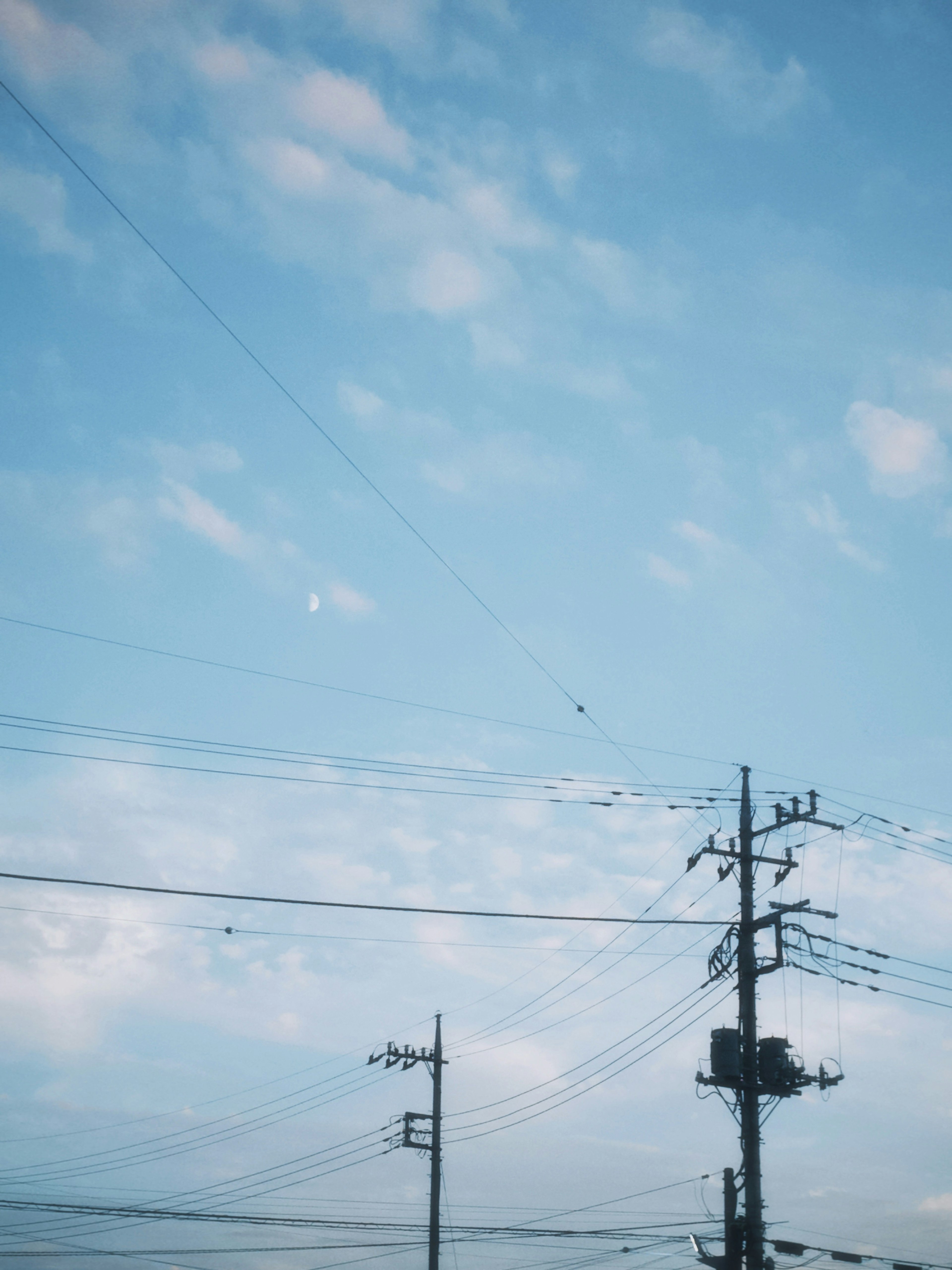 Une vue du ciel bleu avec des nuages blancs et des poteaux électriques