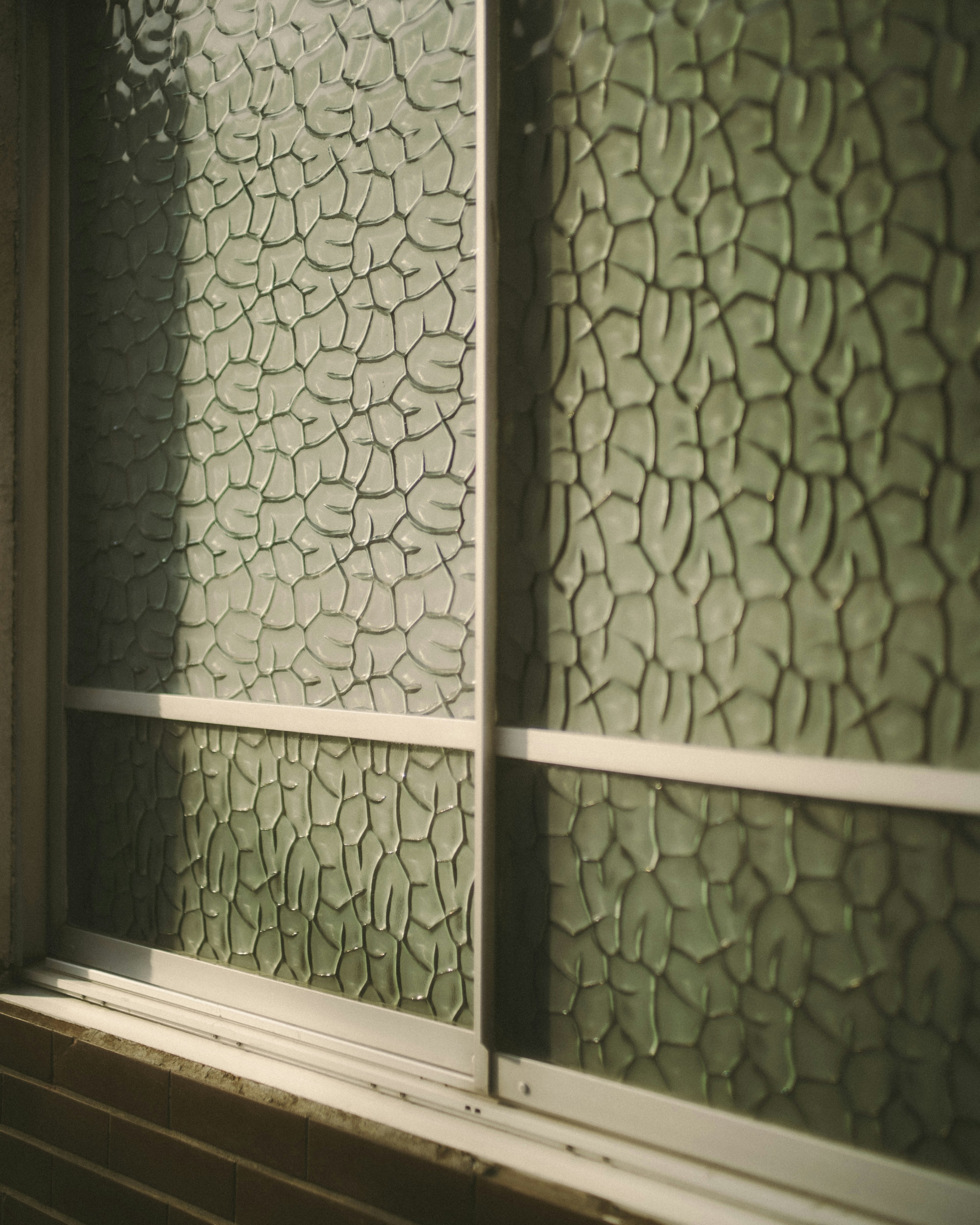 Image of textured green glass window with intricate patterns