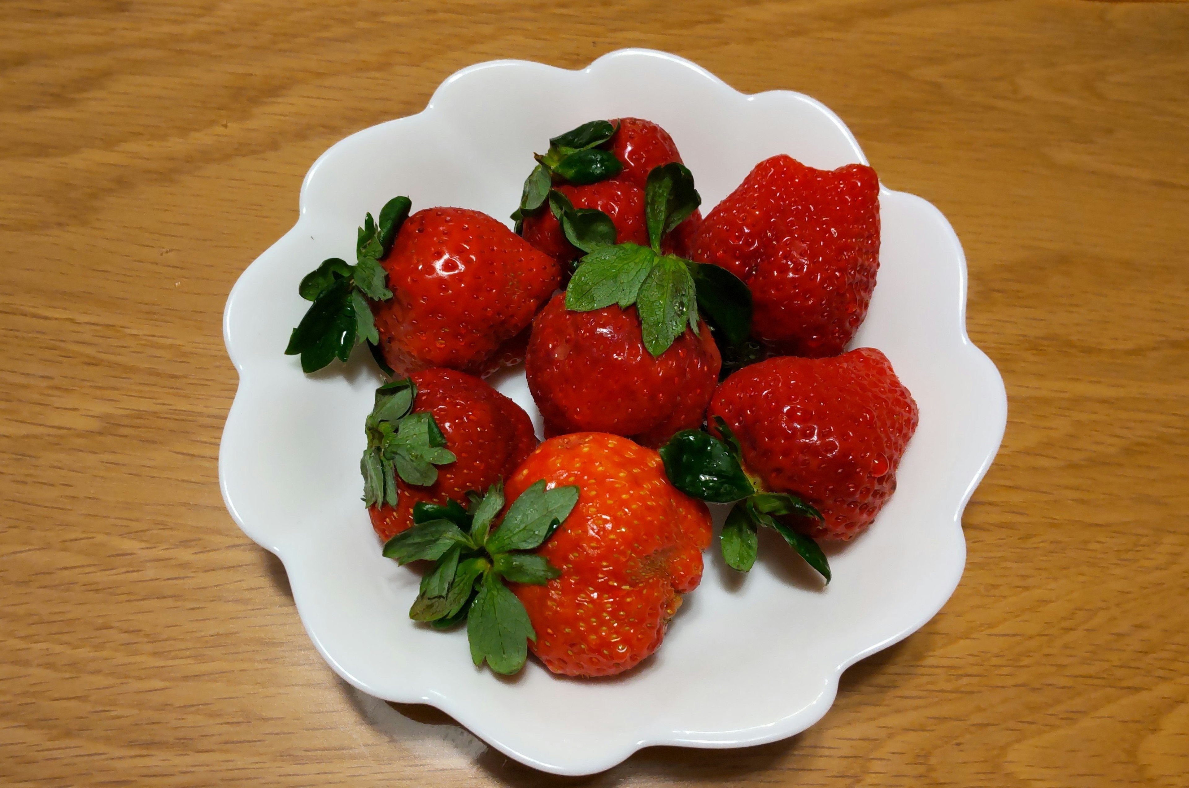 Bowl of fresh strawberries on a wooden surface