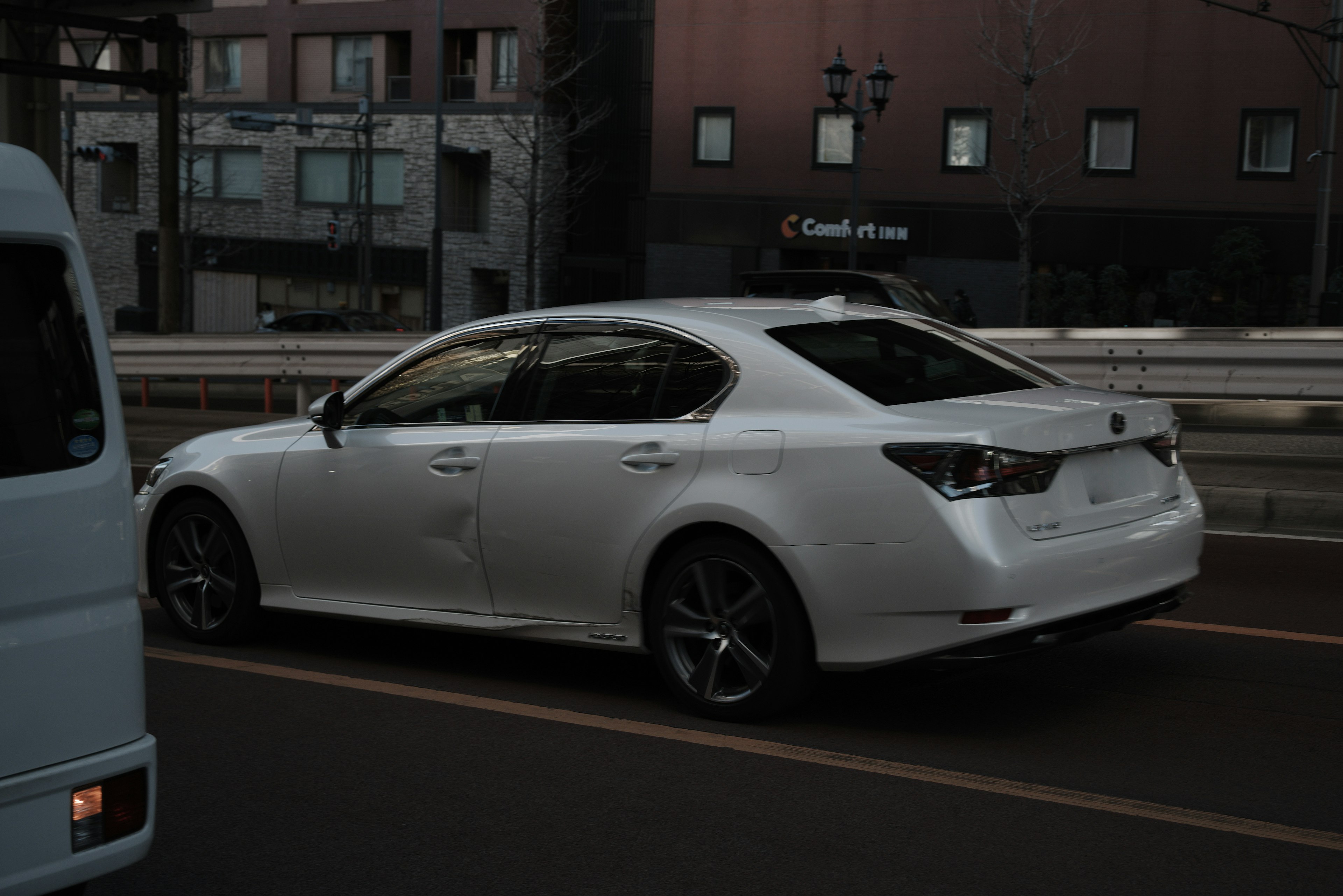 Une voiture berline blanche roulant sur une route urbaine