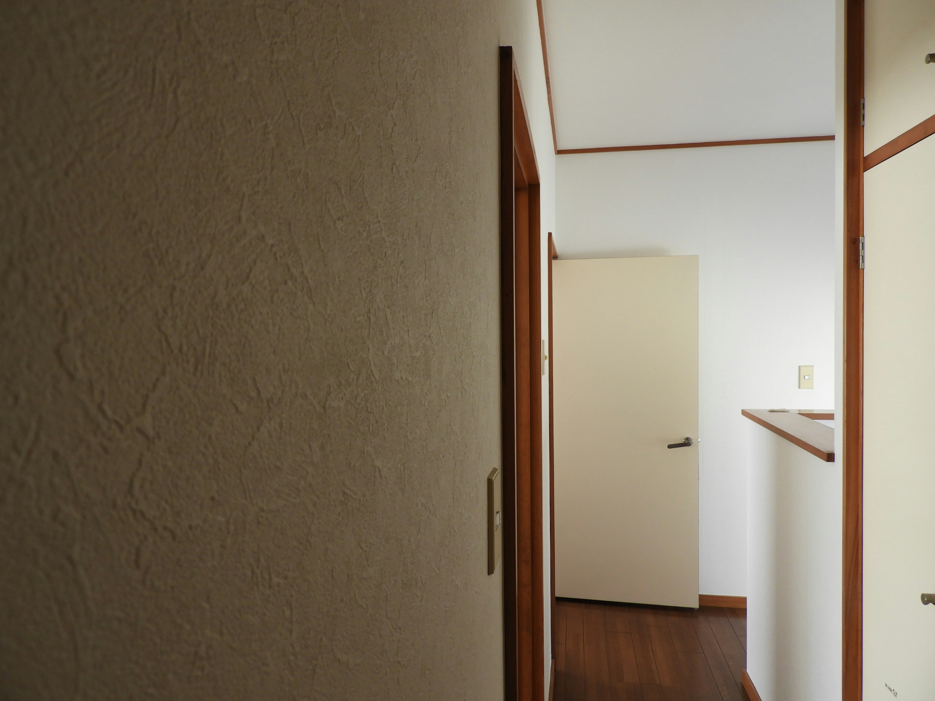 Image d'un couloir lumineux avec des murs blancs et des portes en bois