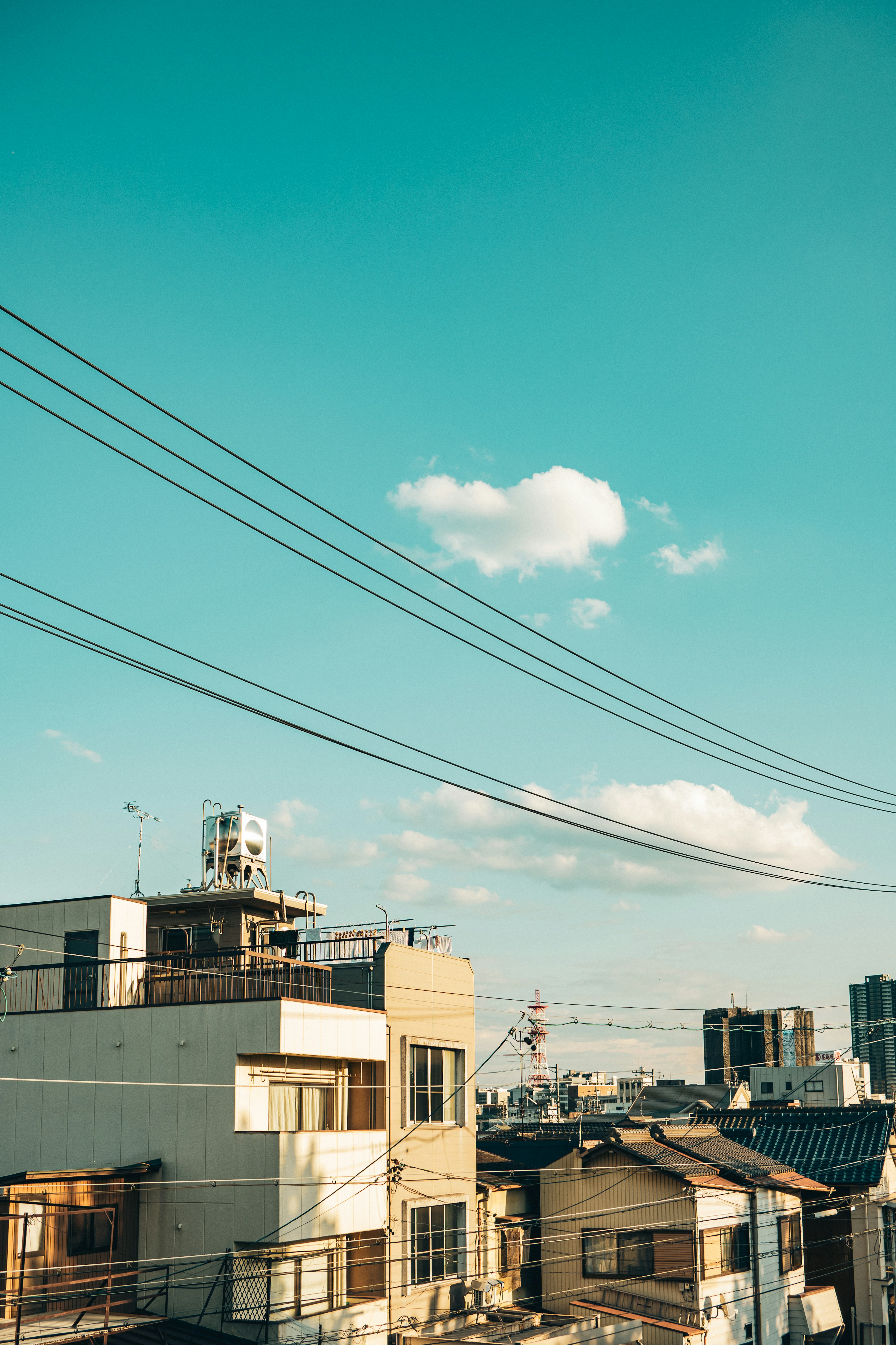 青空と雲の下にある都市の風景 ビルと電線が見える