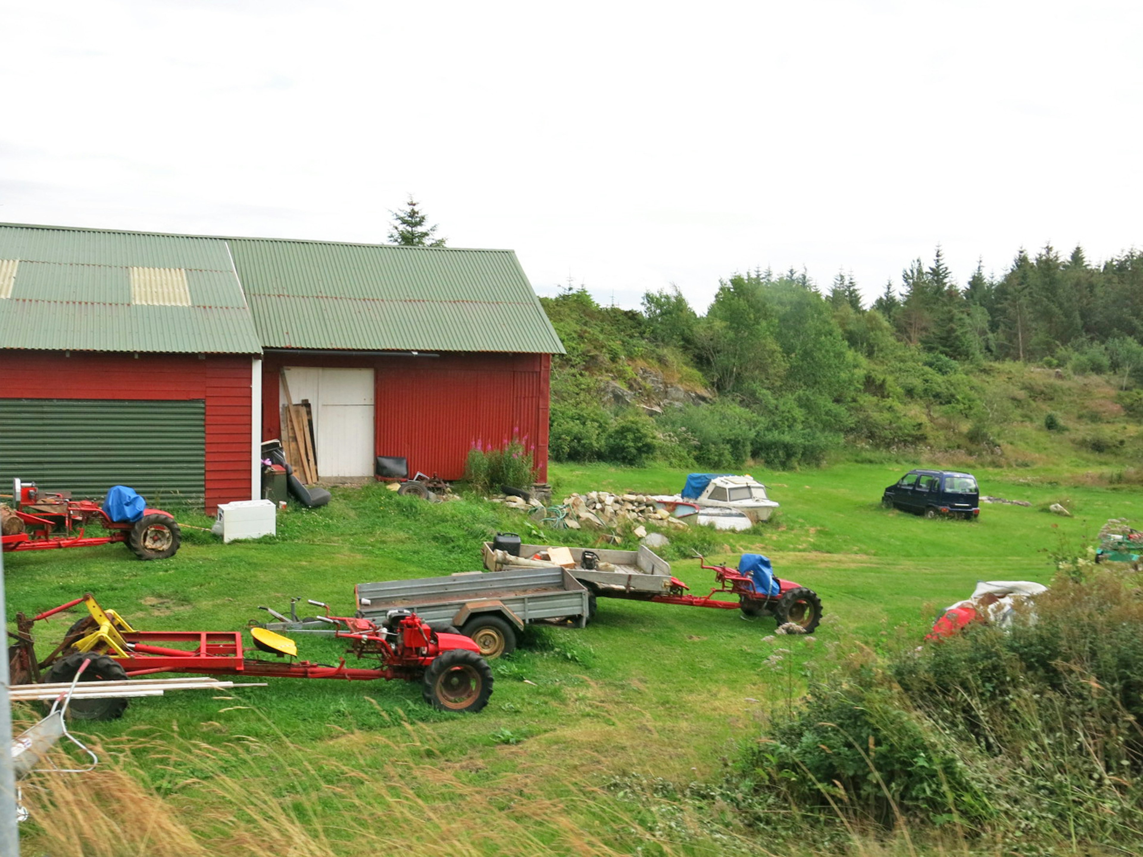 Scène de ferme avec une grange rouge et des travailleurs sur une pelouse verte entourée de véhicules