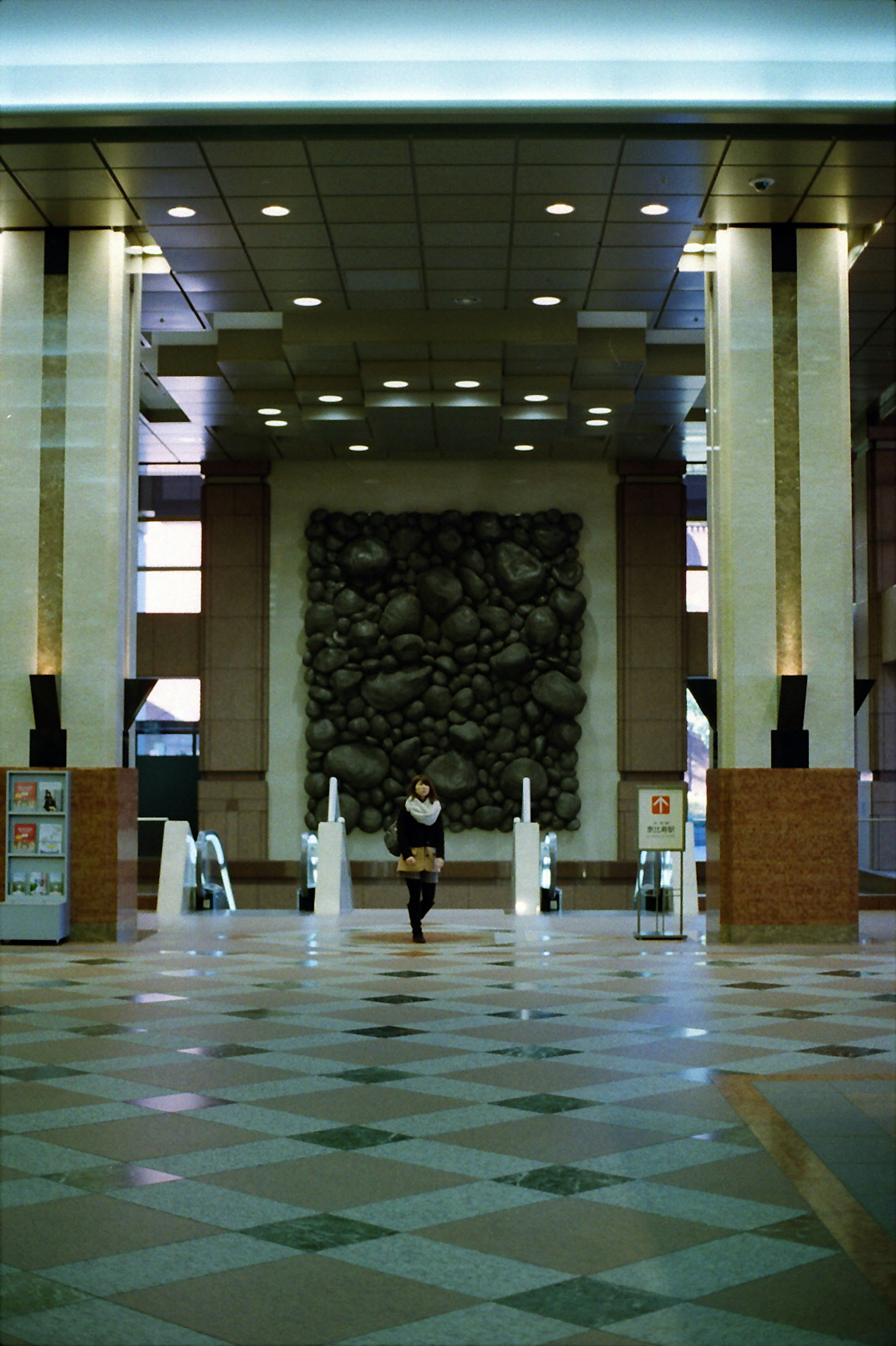 A person standing in a spacious lobby with a sculptural background