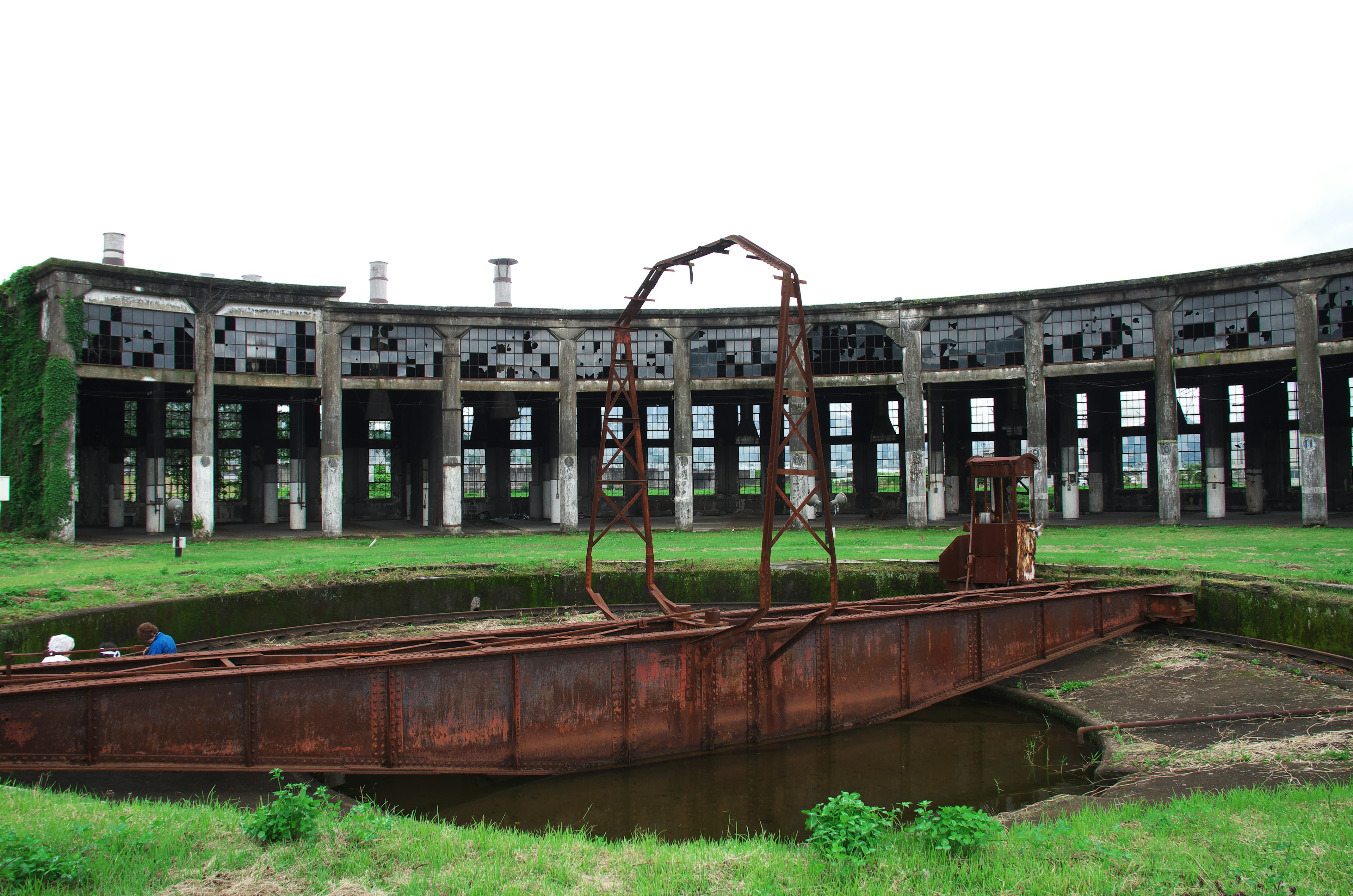 Estructura abandonada con un barco oxidado rodeado de hierba verde