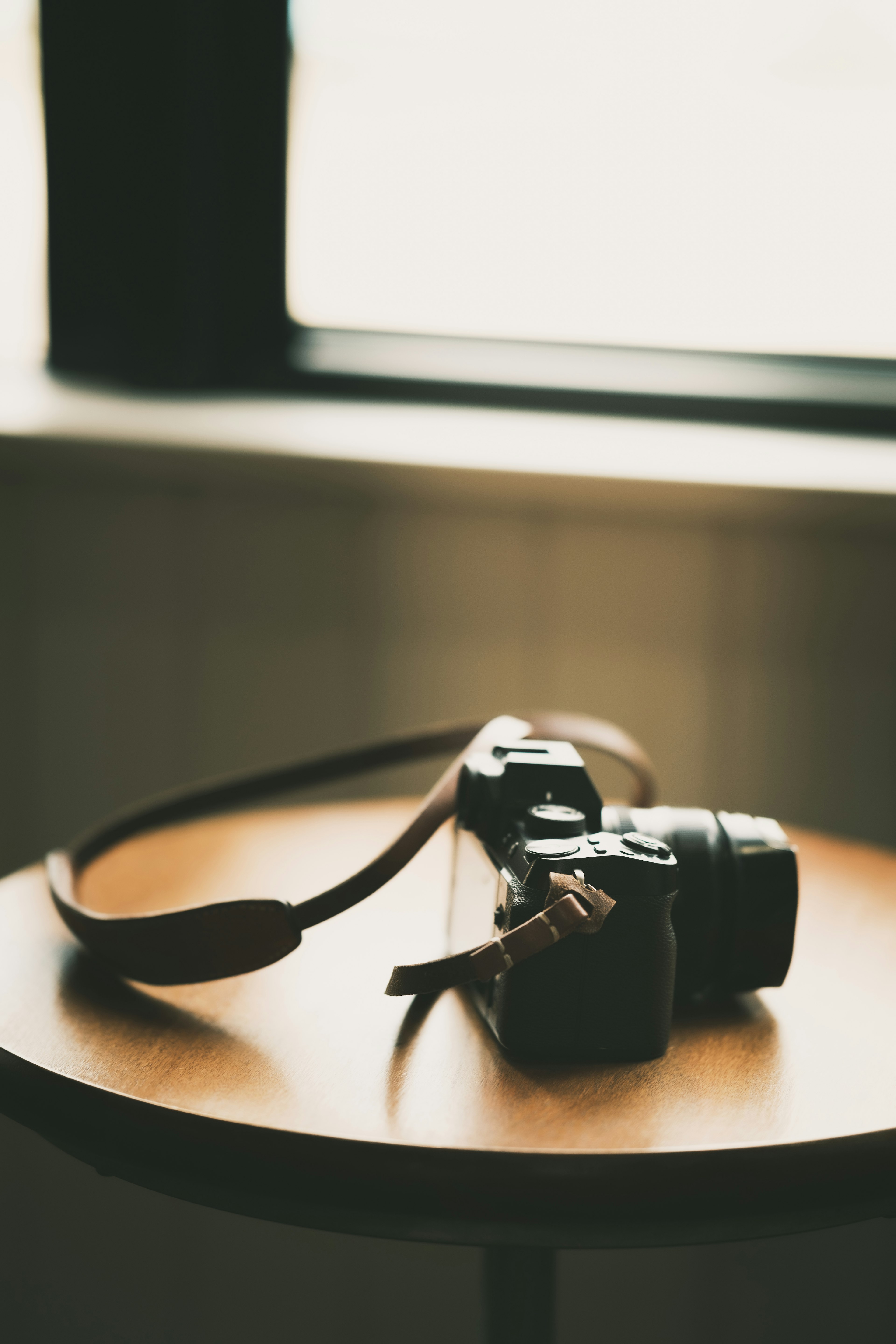 Image of a camera with a strap on a table near a window