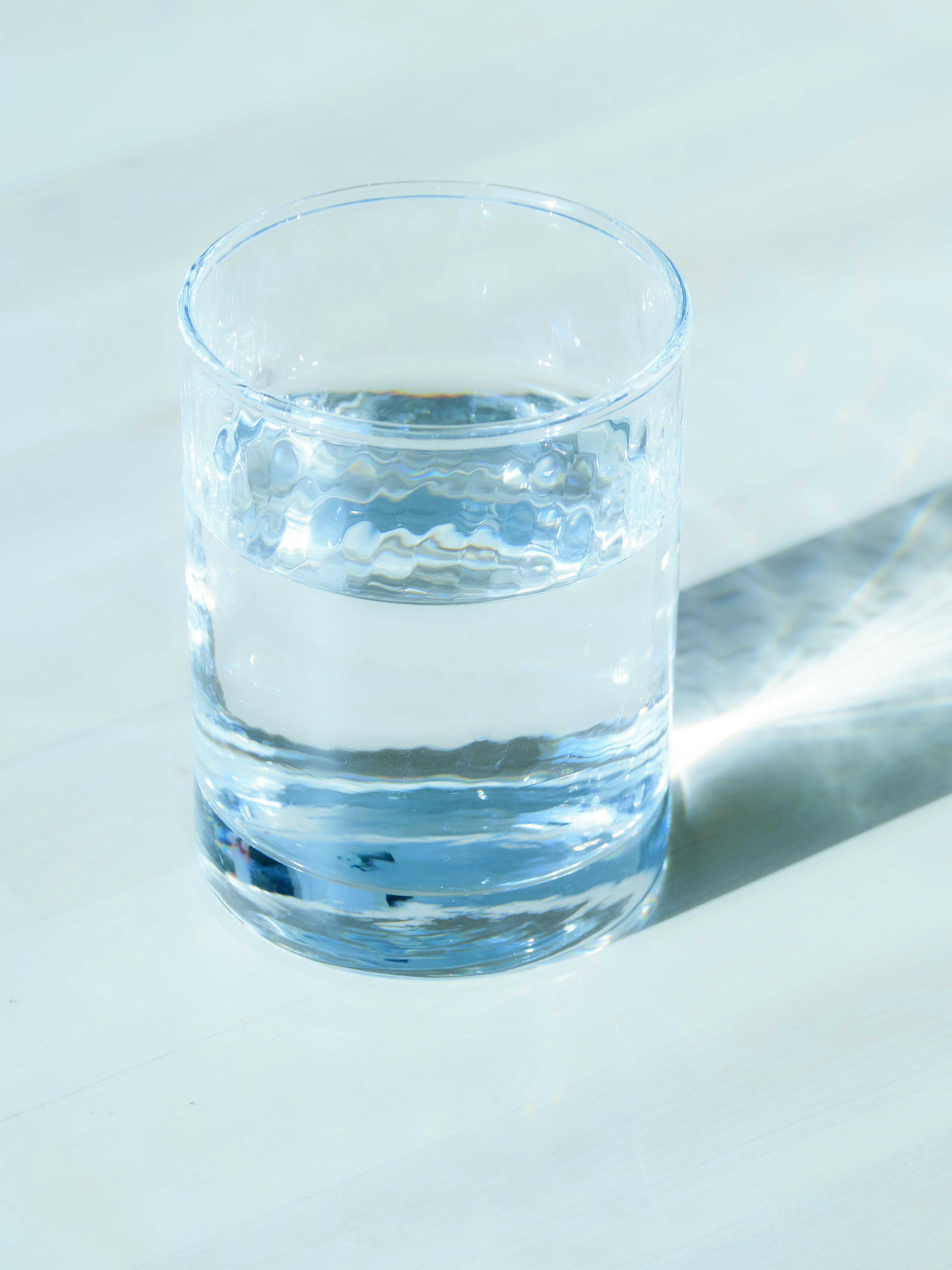 Image of a clear glass filled with water casting a soft shadow