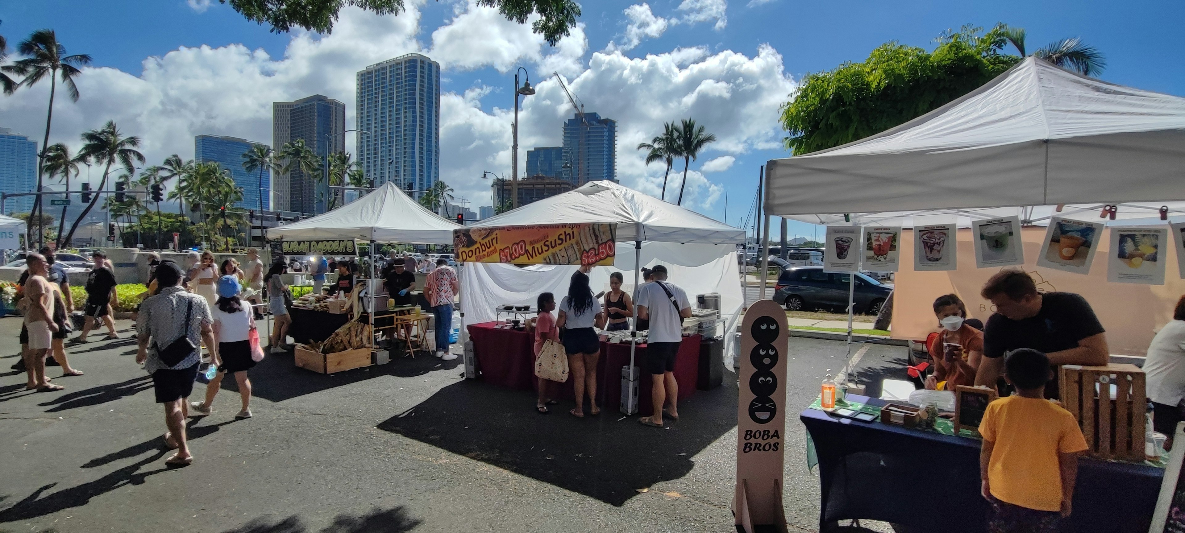 A bustling market scene under a blue sky with tents and people