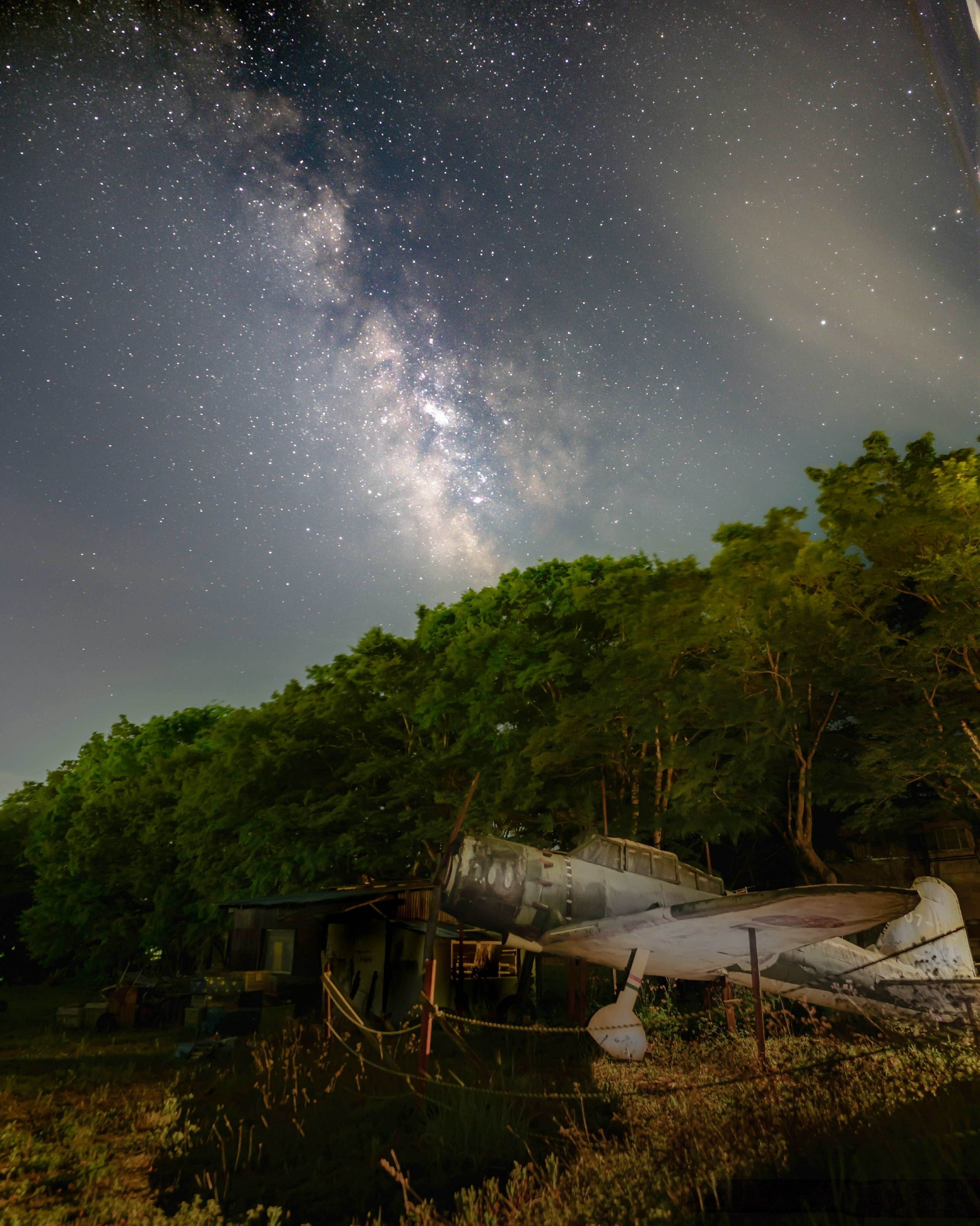 Un vecchio aereo sotto un cielo stellato con la Via Lattea visibile