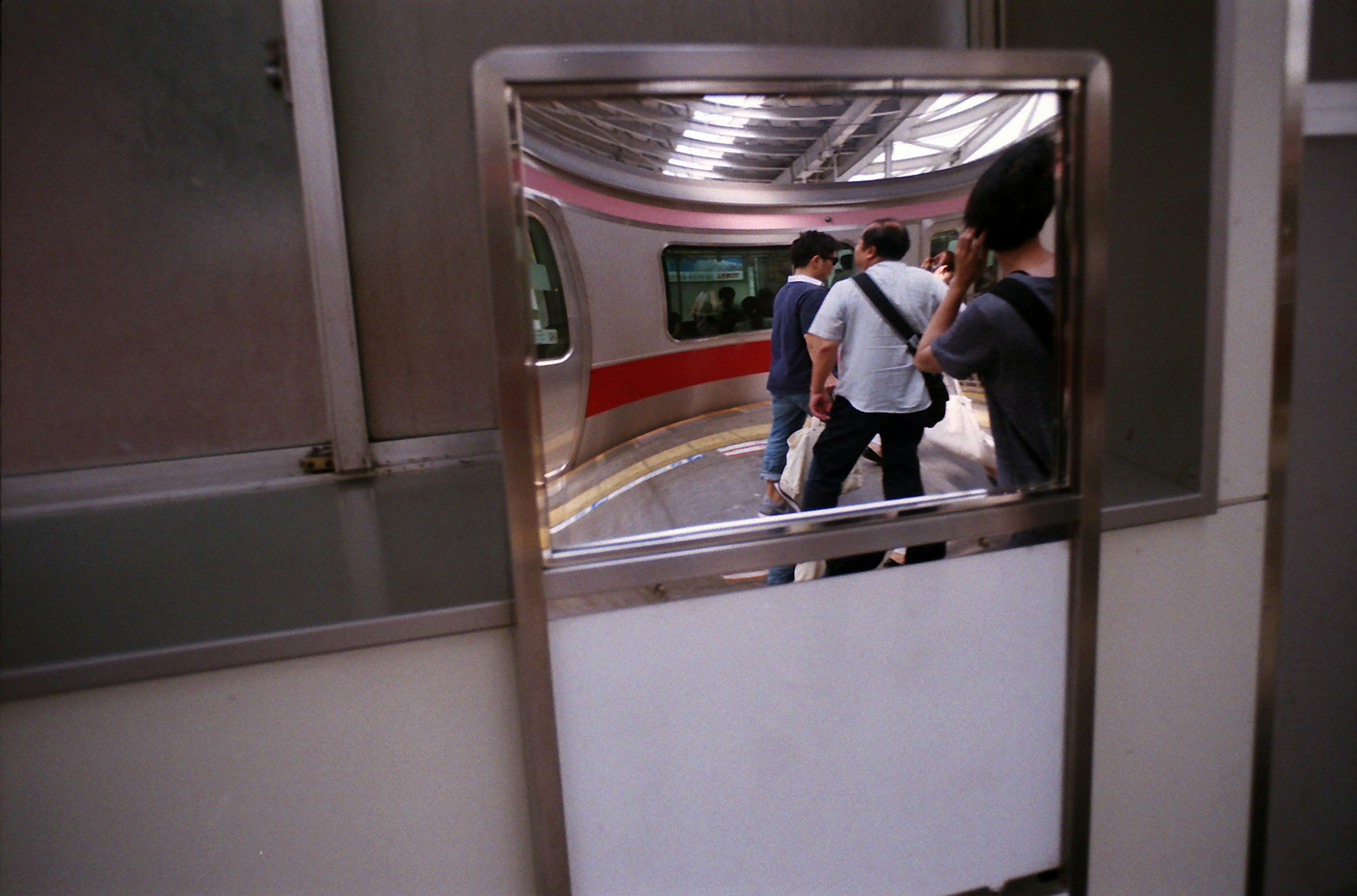 Riflesso di passeggeri e treno in uno specchio di stazione della metropolitana