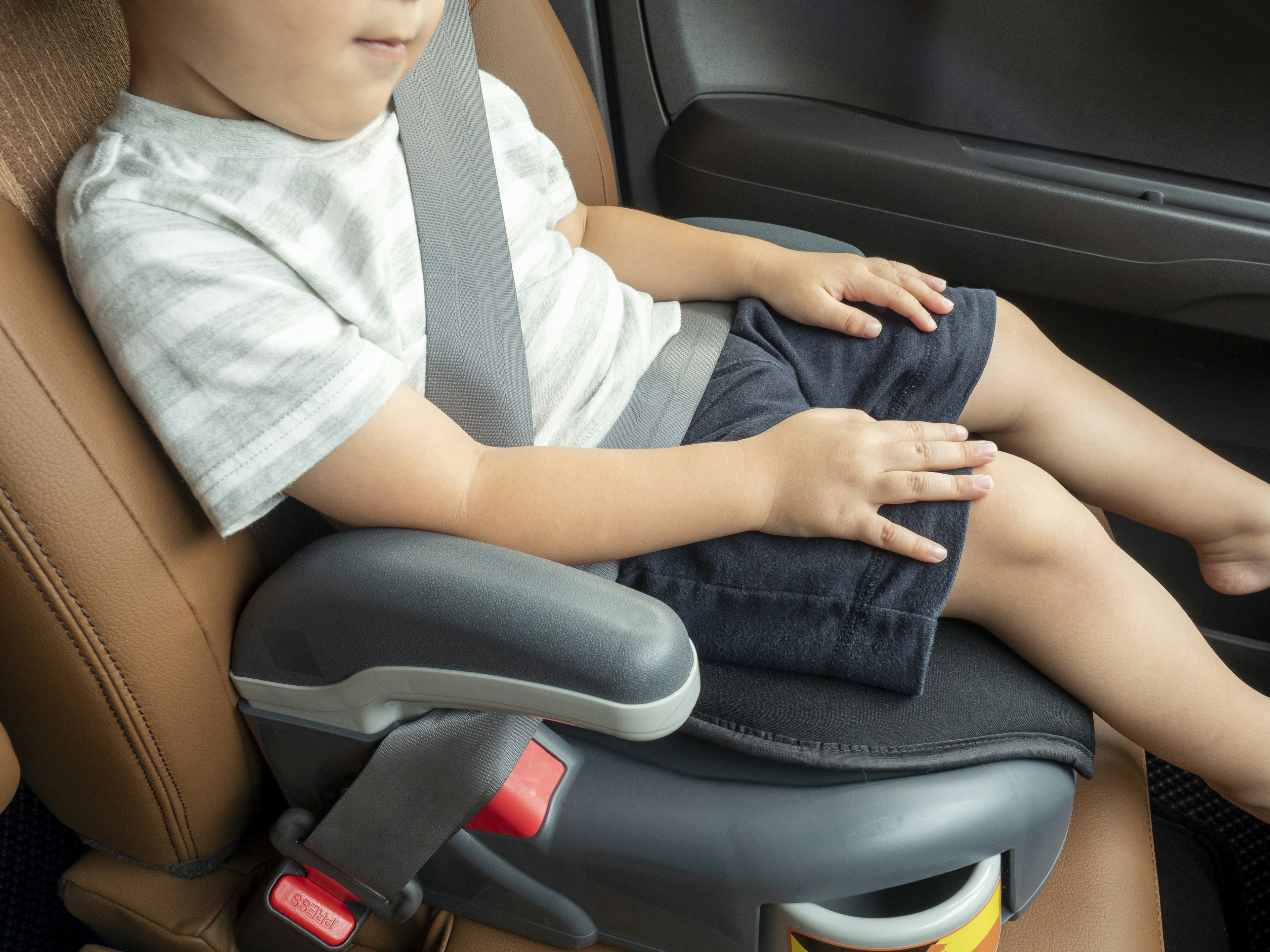 Niño sentado en un asiento de automóvil con cinturón de seguridad