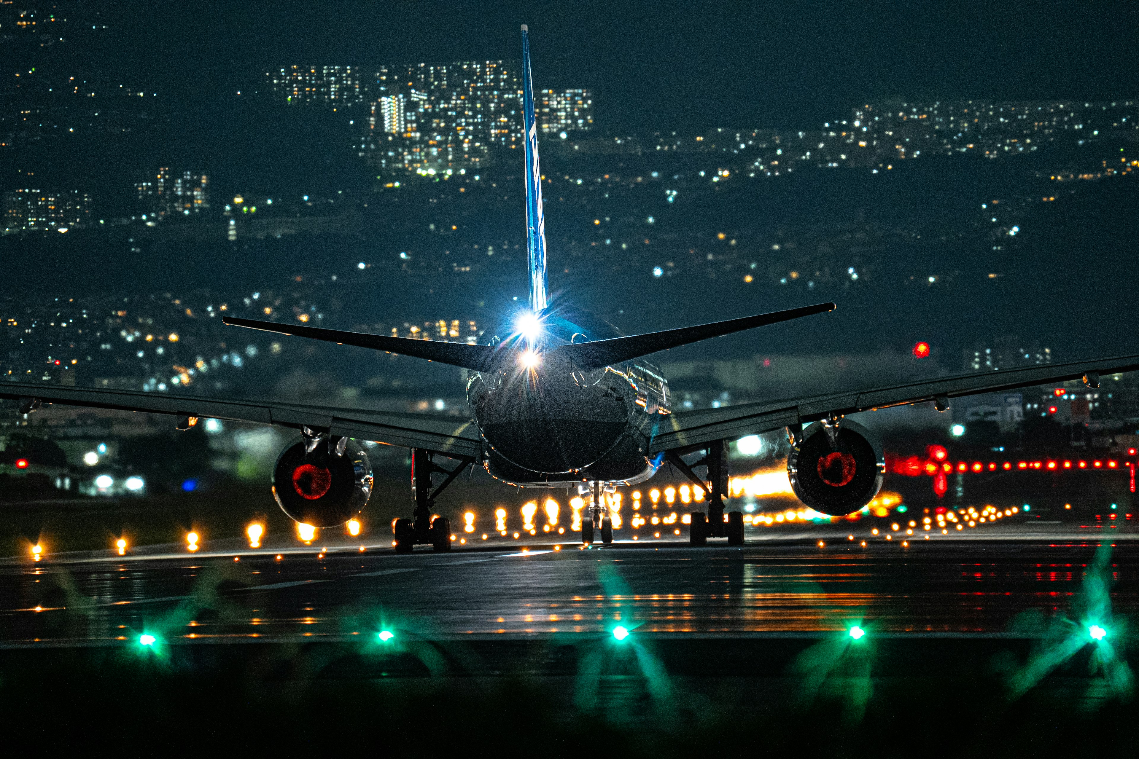 夜間在跑道上著陸的飛機後視圖，配有明亮的燈光