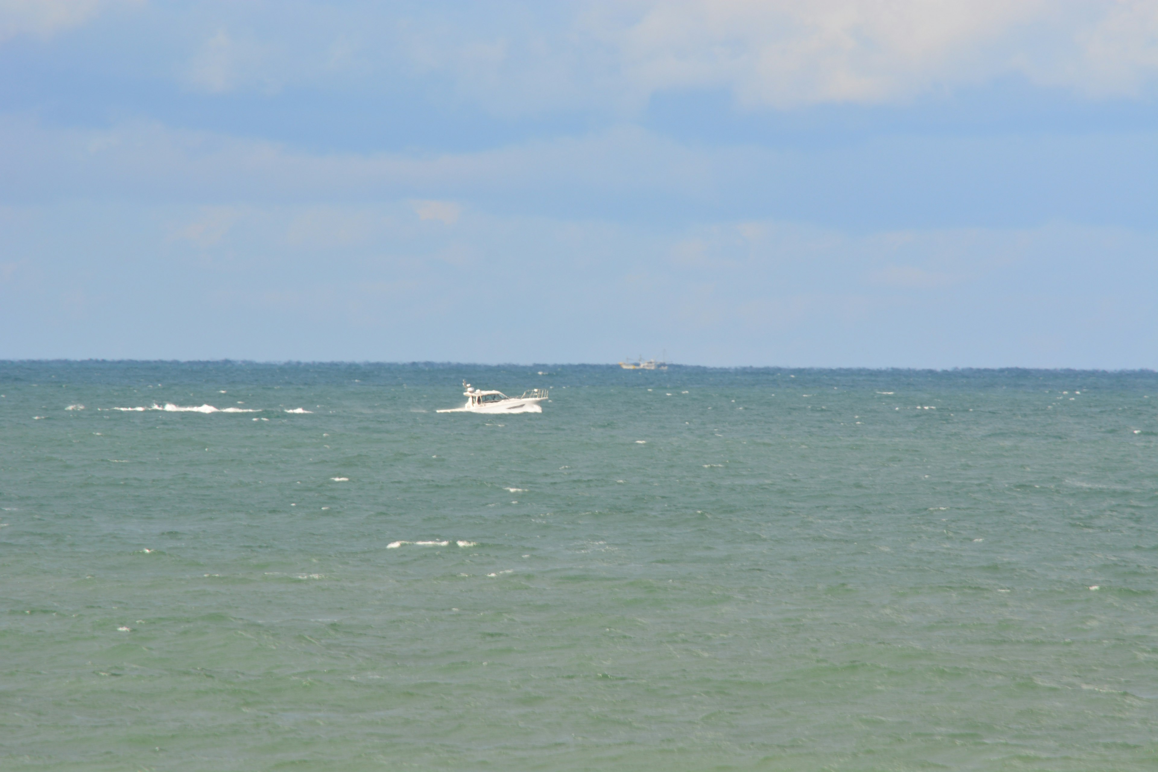 Un petit bateau flottant sur une mer bleue sous un ciel nuageux