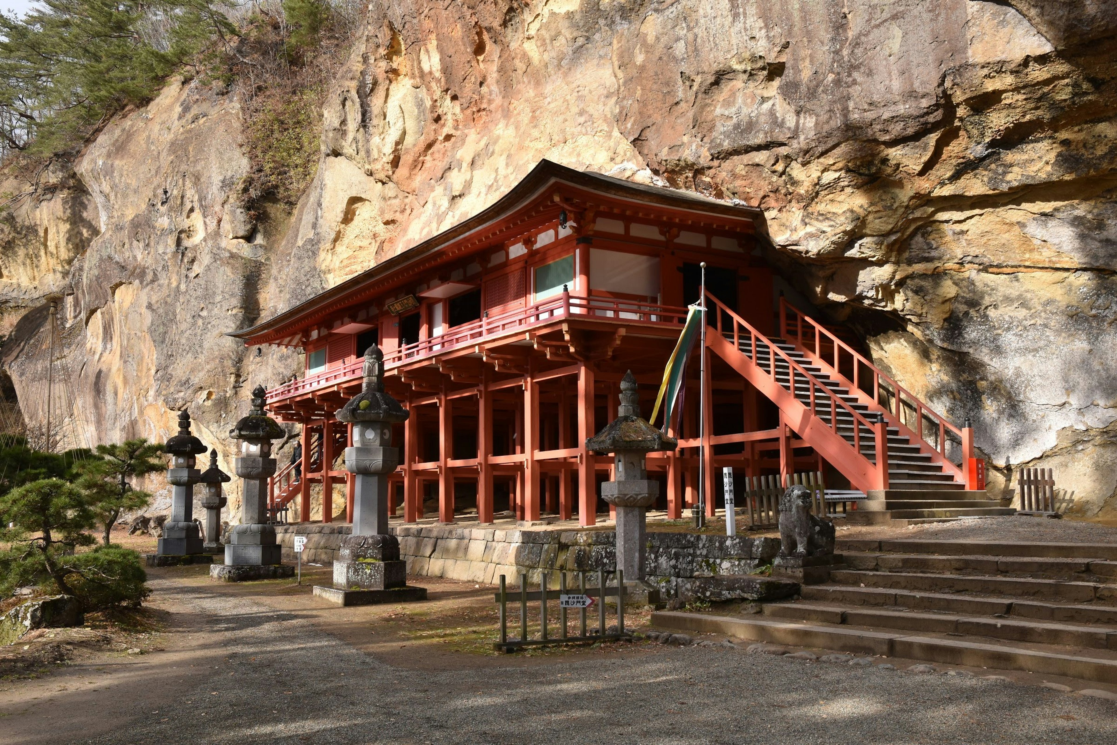 Tempio rosso vicino a una scogliera con statue di pietra