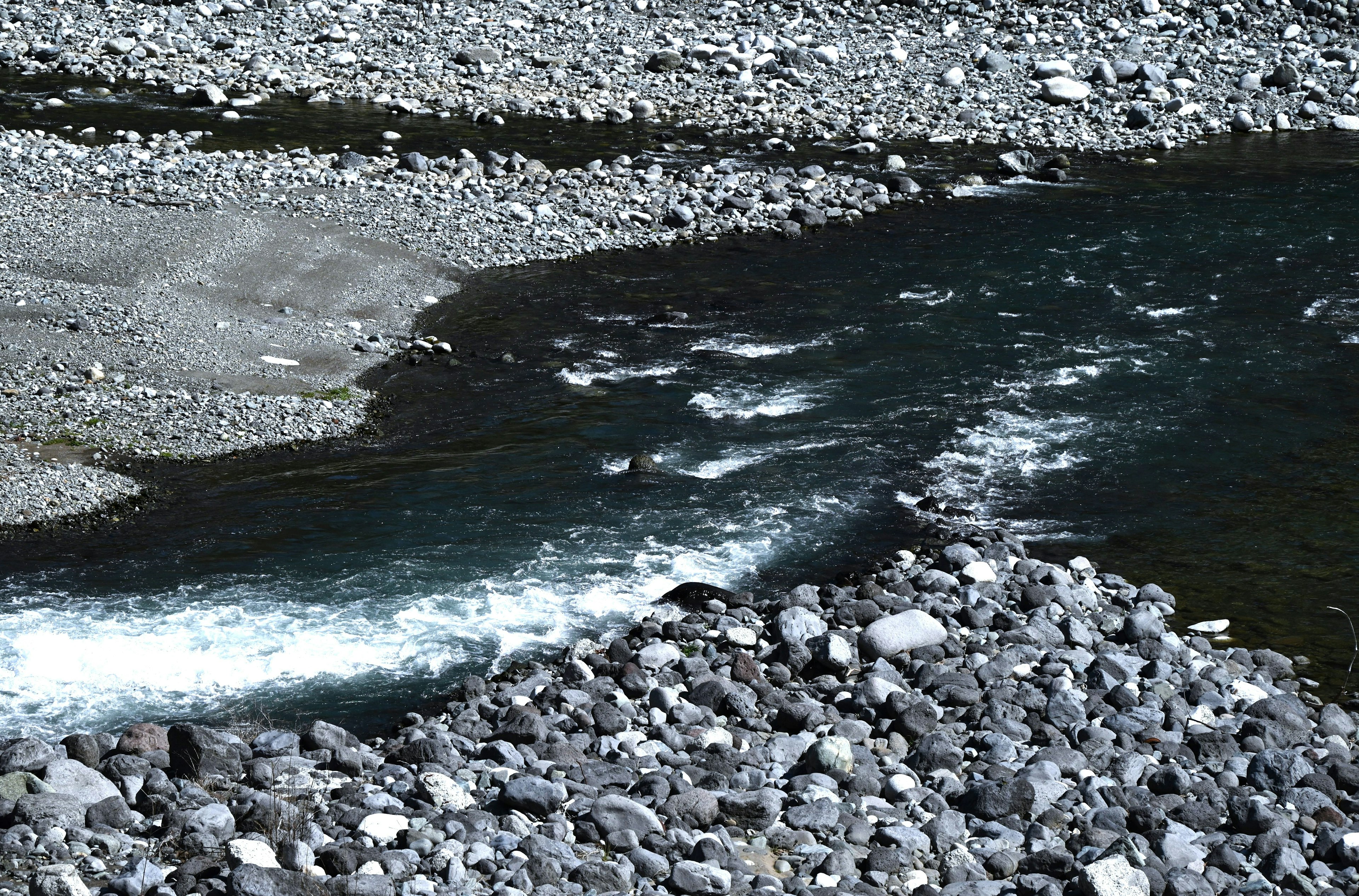 Ruscello che scorre su una riva rocciosa con ciottoli e increspature