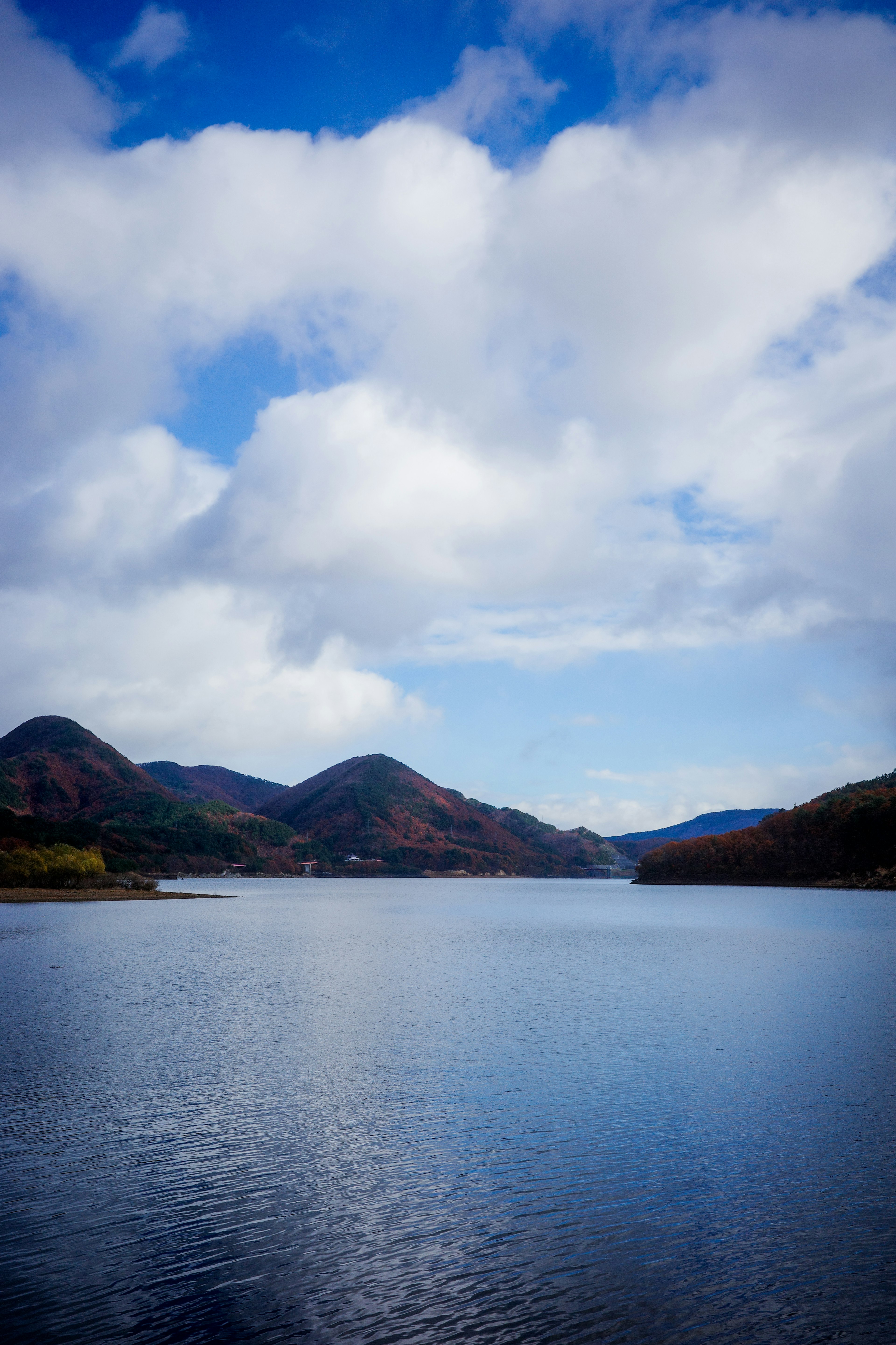 青い空と雲が広がる湖の風景 山々が水面に映る