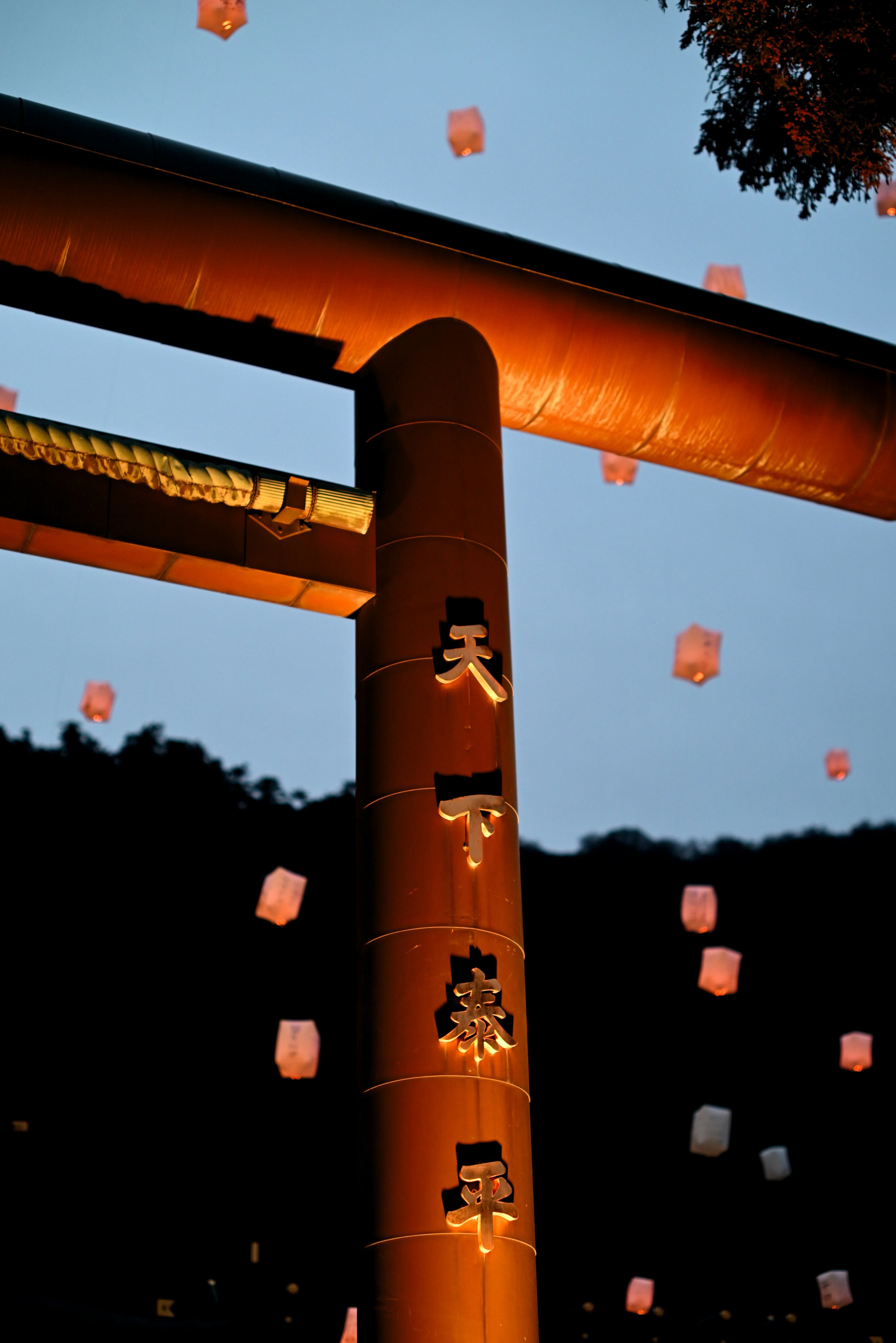 Torii-Tor beleuchtet in der Dämmerung mit schwebenden Laternen