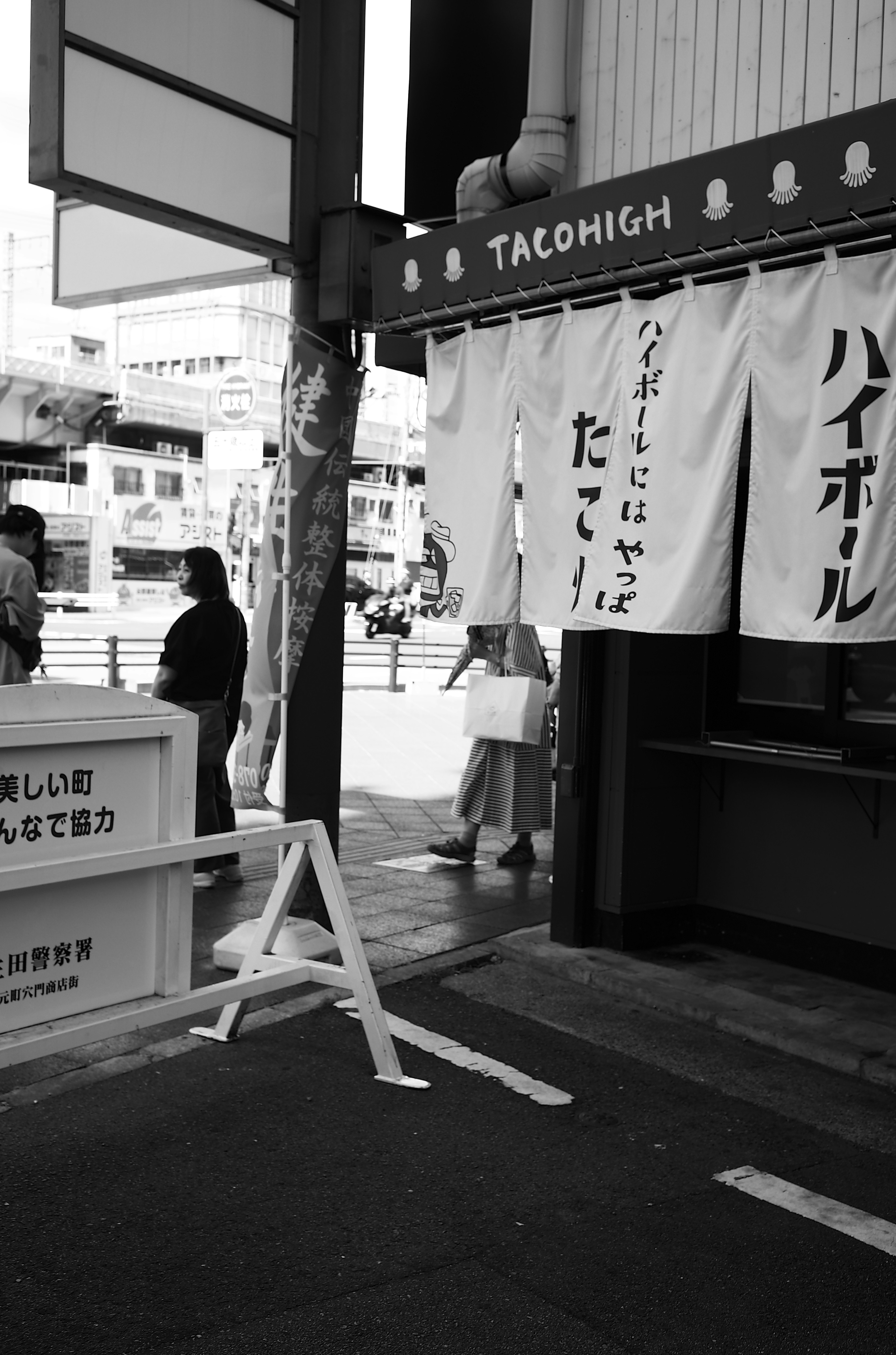 タコハイの看板と白い布の垂れ幕がある街の風景