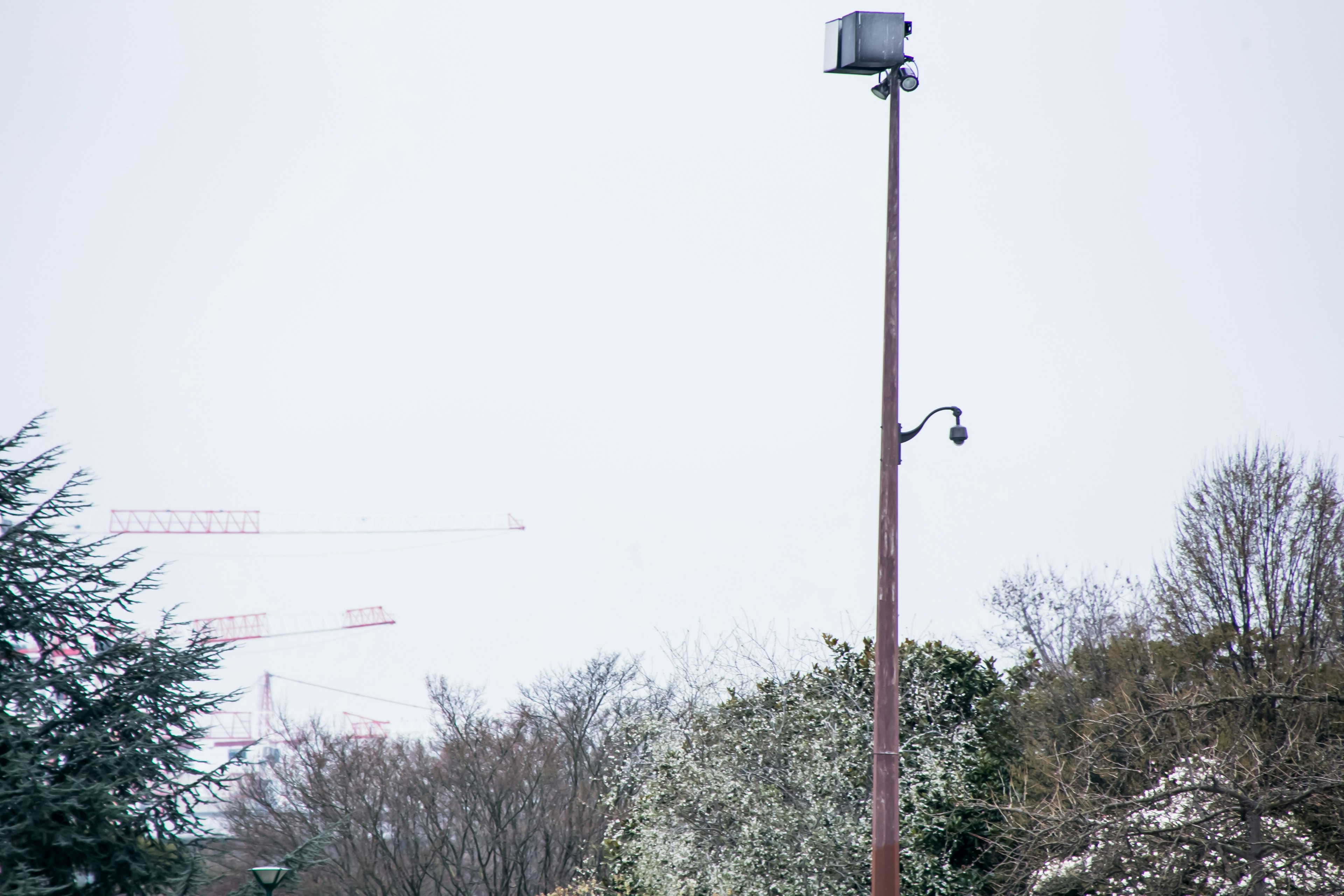 Un alto poste con un altavoz y una cámara bajo un cielo nublado