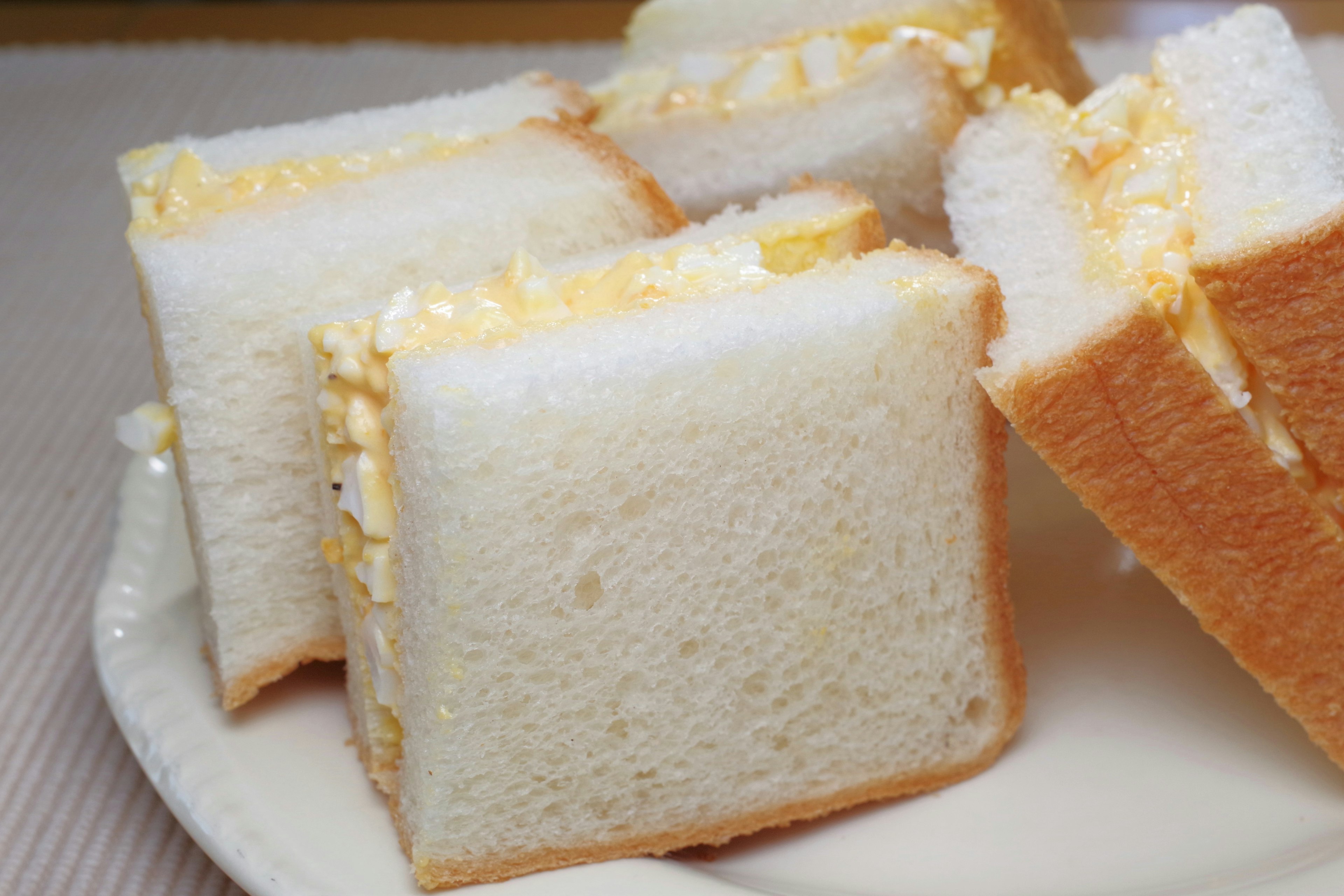 Piezas de sándwich de huevo en rodajas sobre un plato blanco