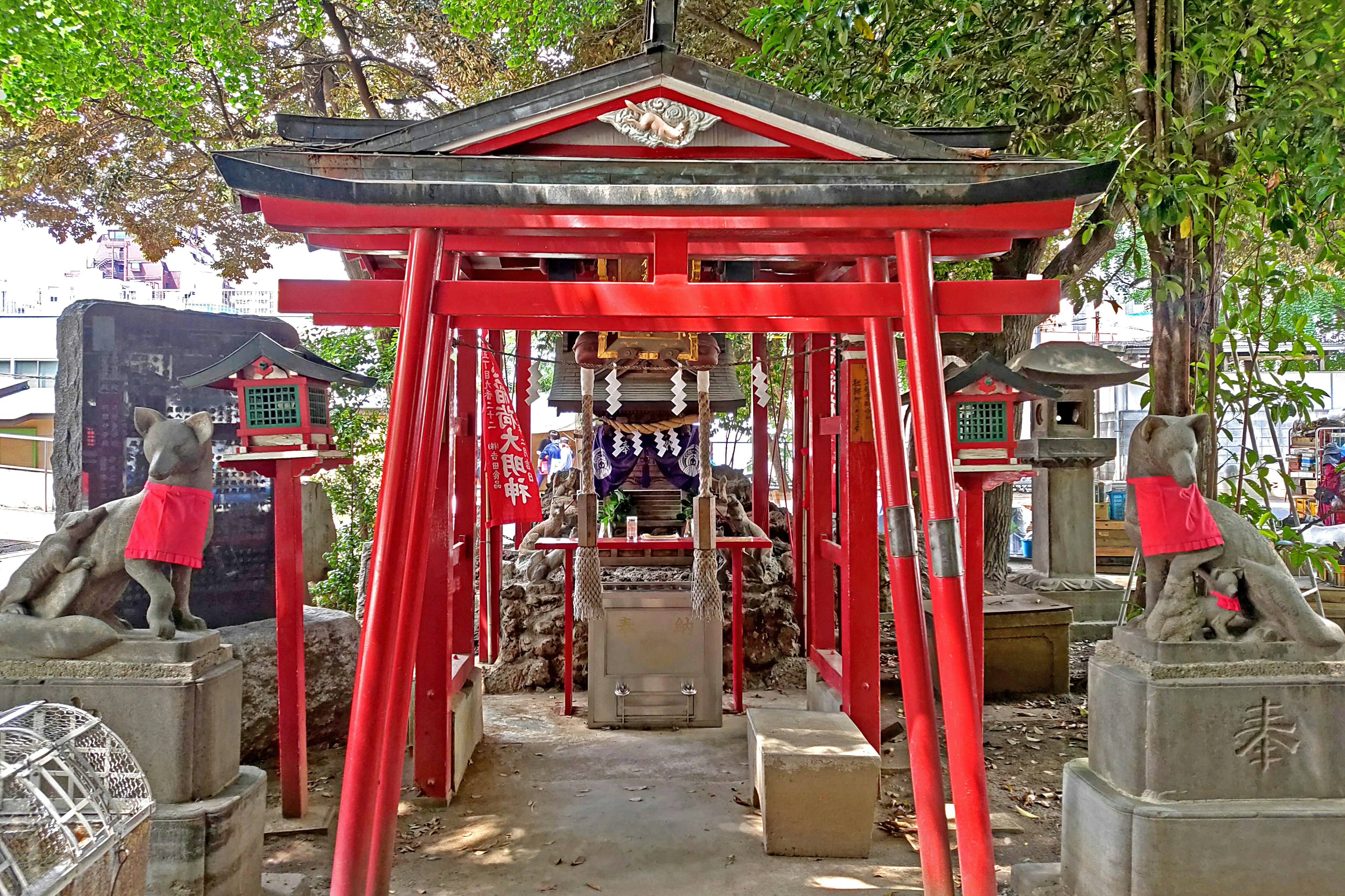 Entrata di un santuario con torii rossi e statue di pietra circostanti