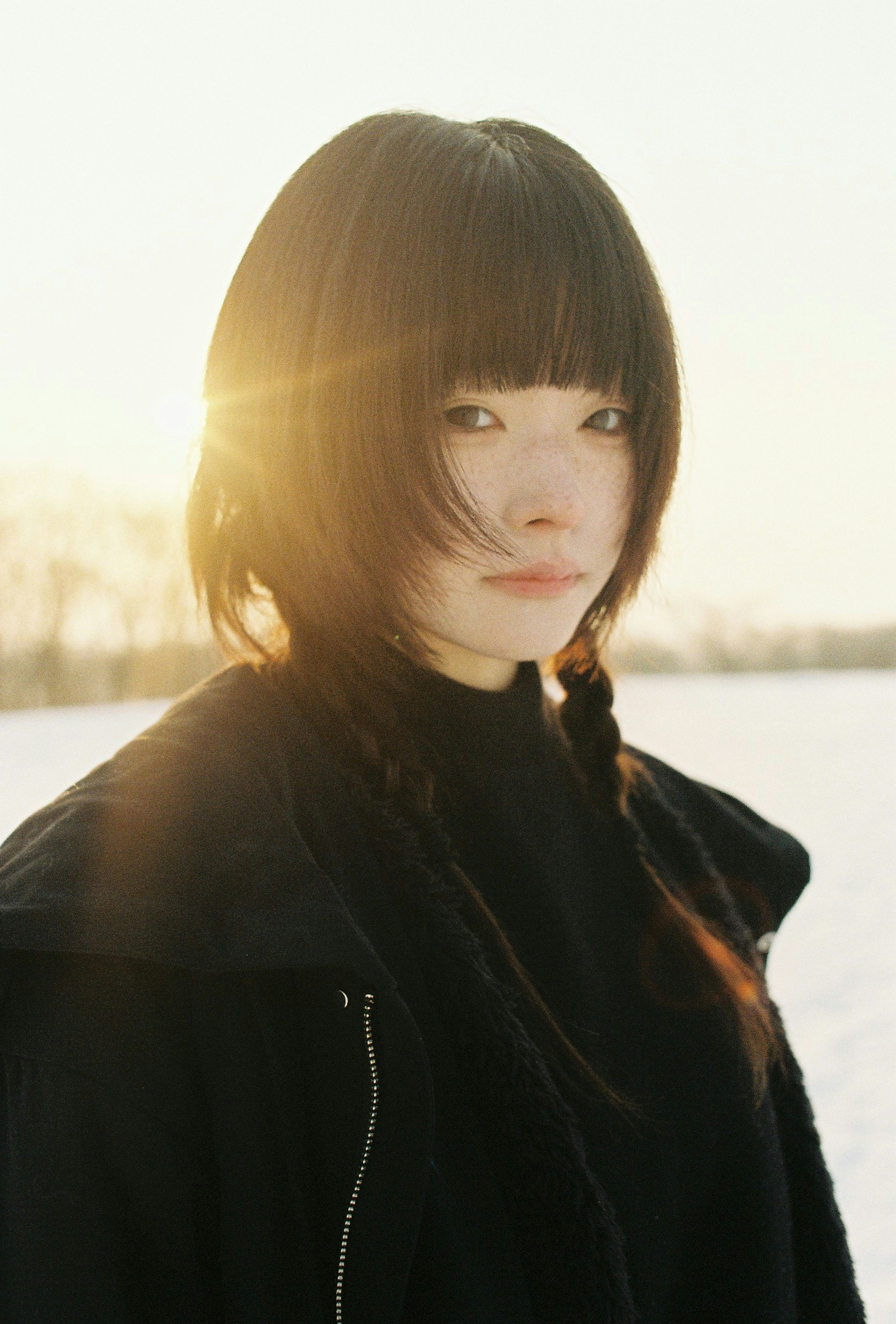 冬の風景の中で黒い服を着た少女のポートレート