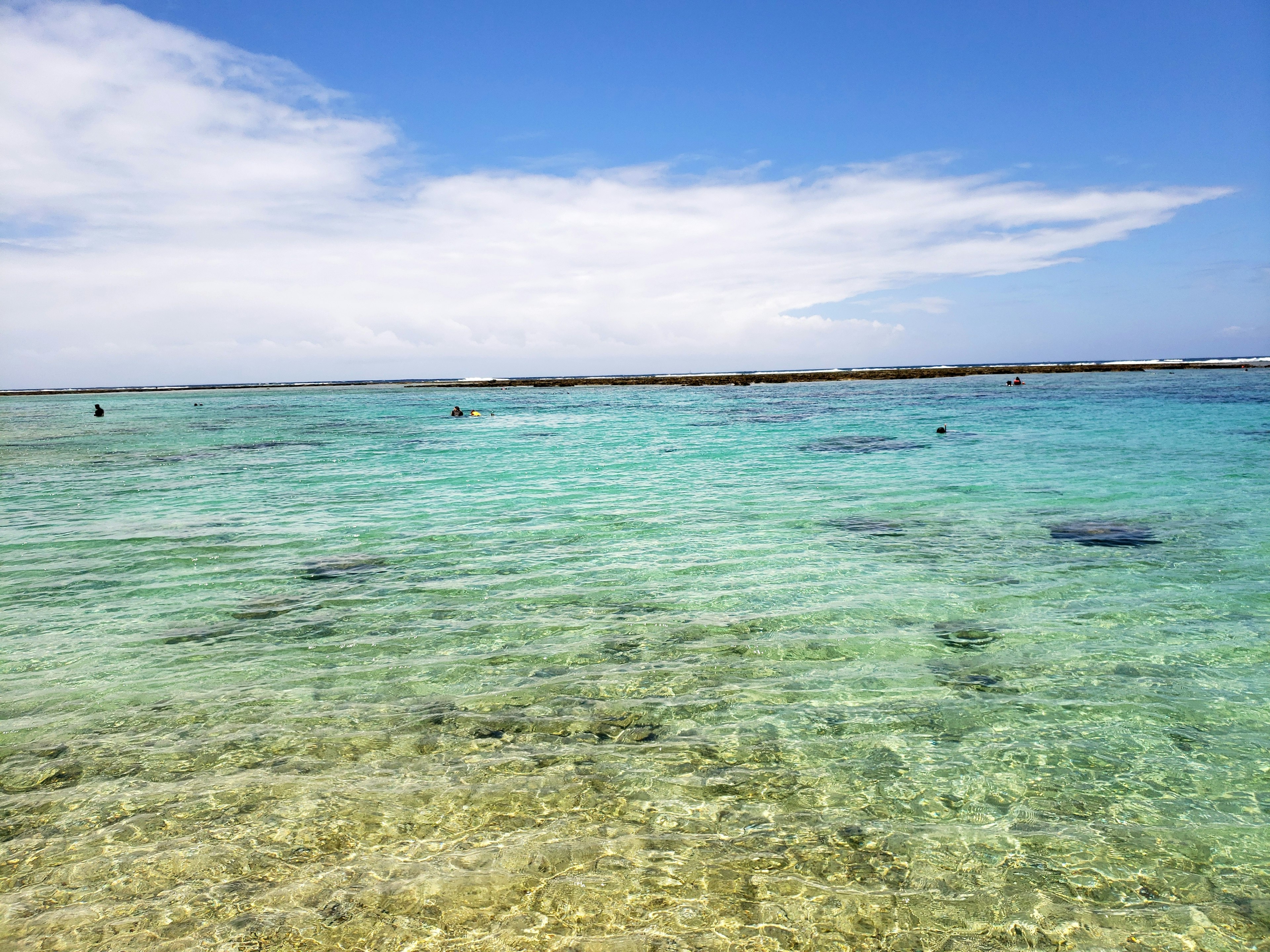 Eau turquoise claire sous un ciel bleu avec des nuages épars