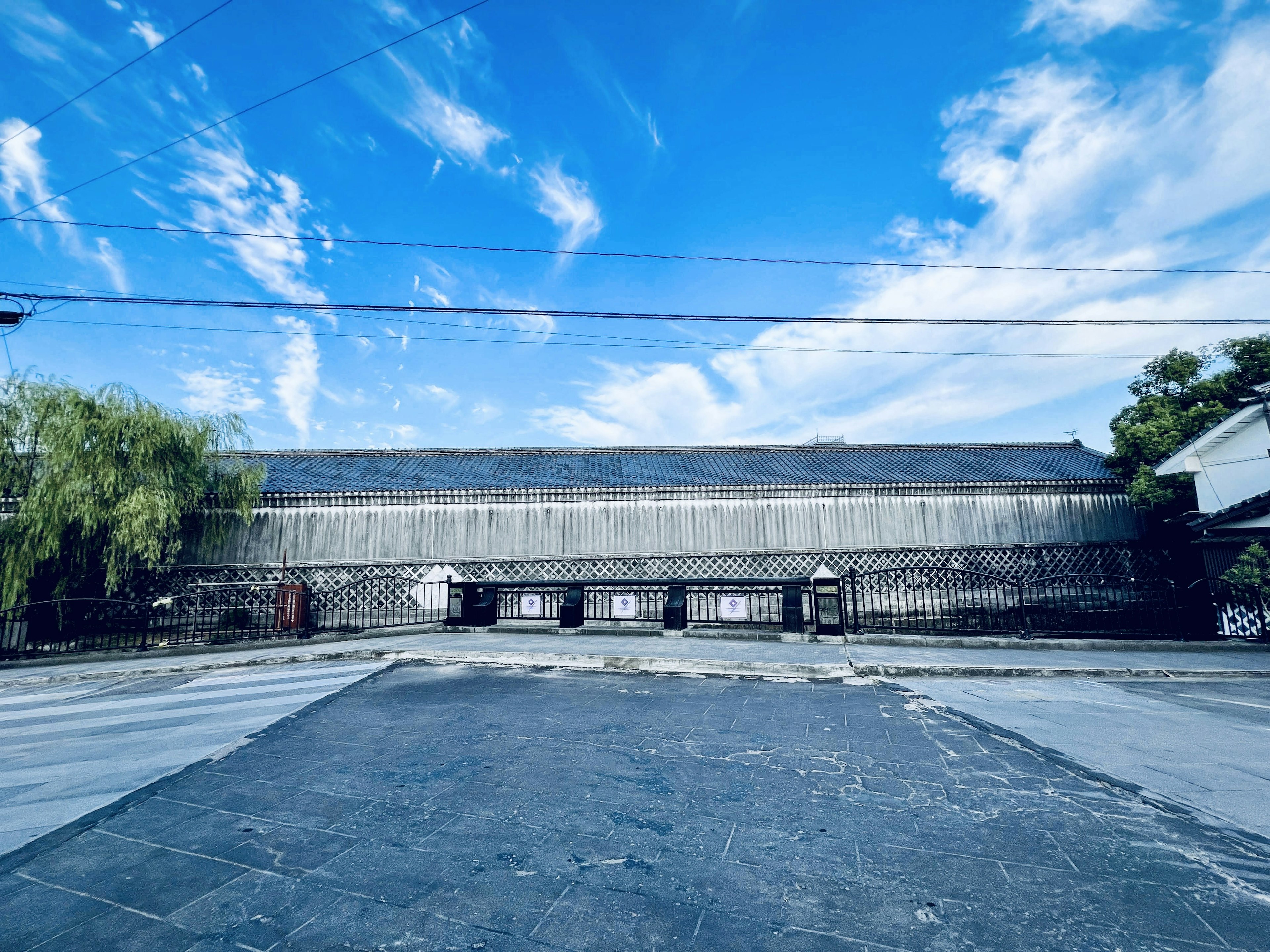 A view of an old building under a blue sky featuring a stone exterior and a spacious square