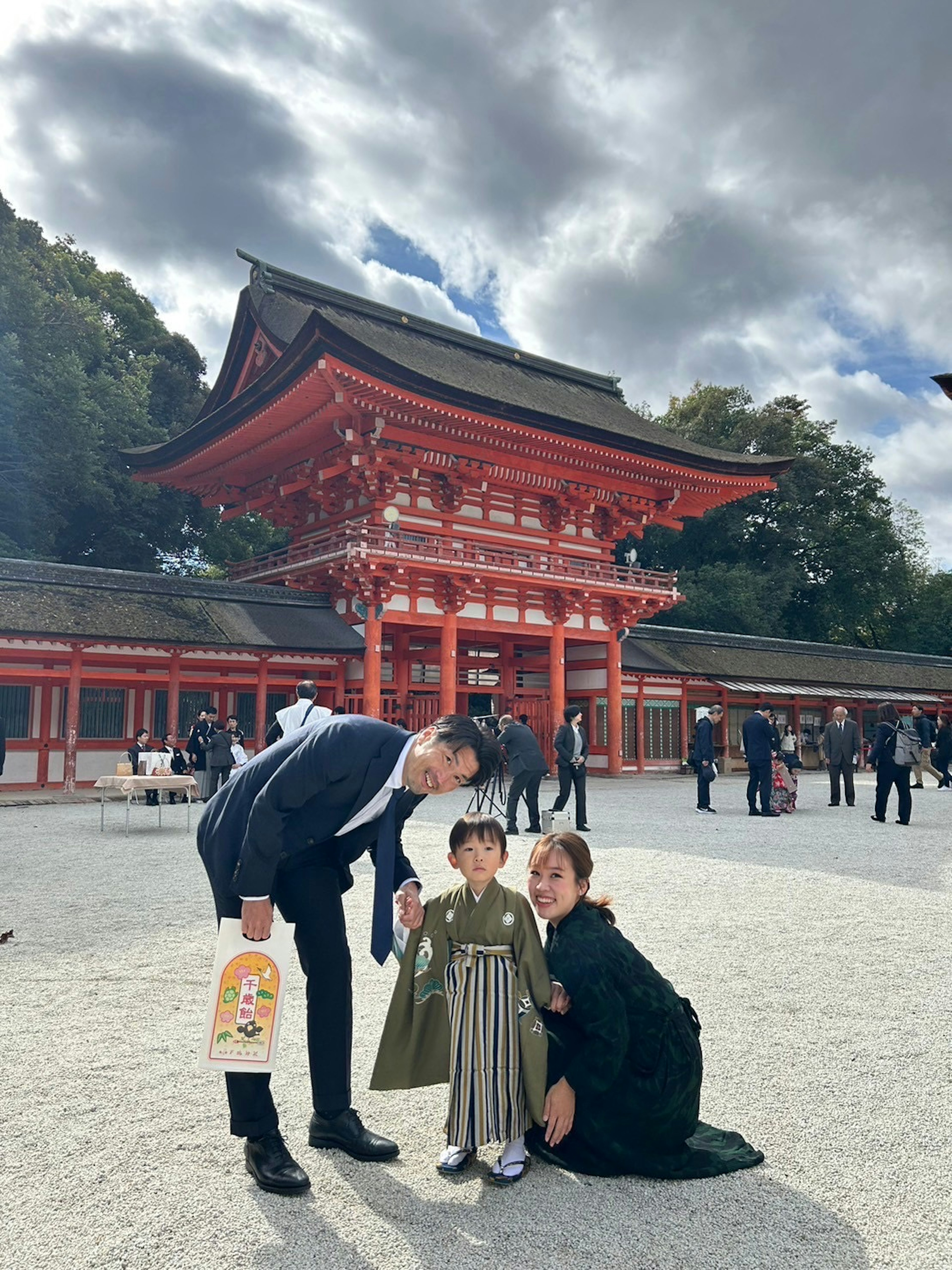 赤い神社の前で家族がポーズをとる子供が伝統的な衣装を着ている