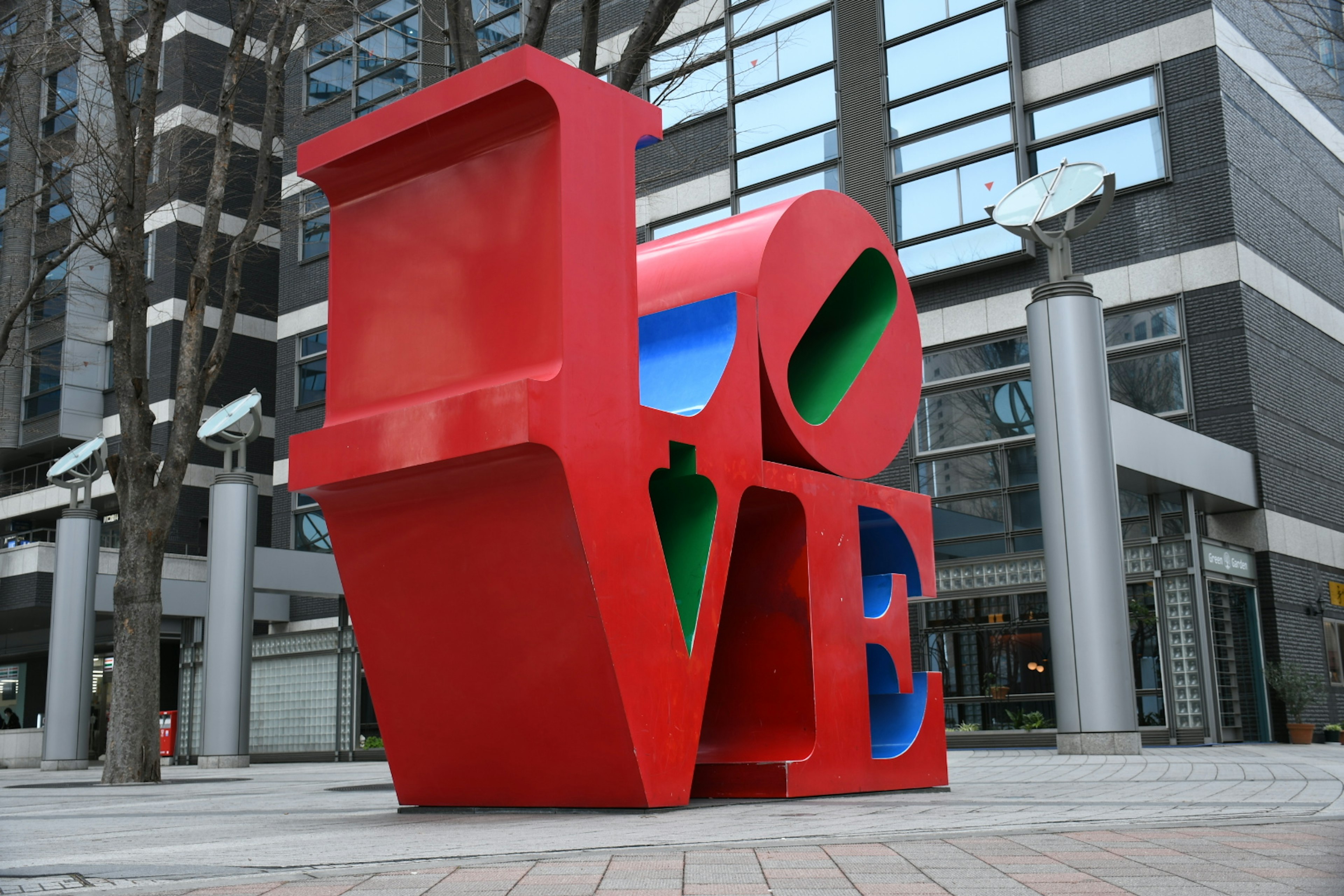 Large red LOVE sculpture stands in an urban setting