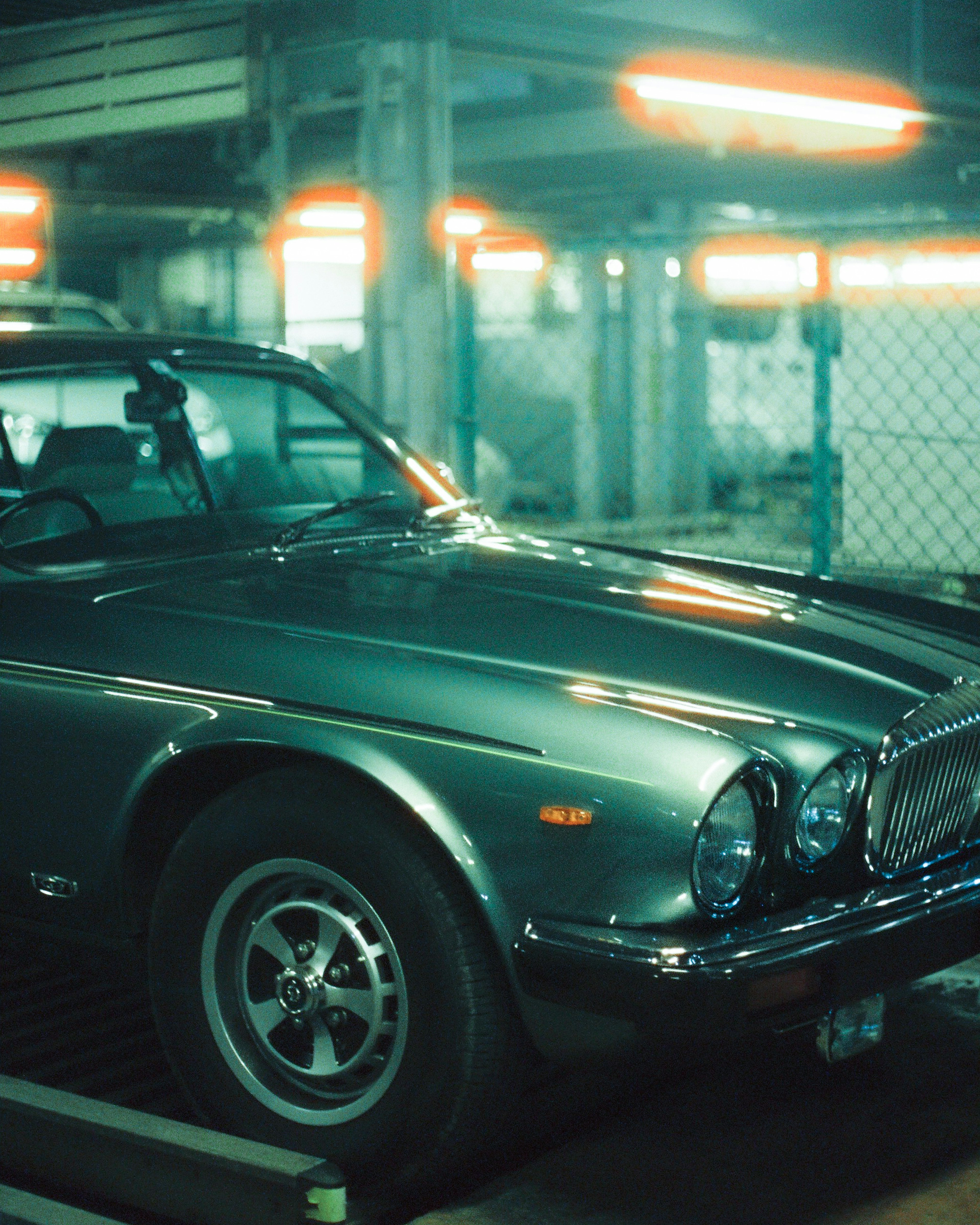 Close-up of an old Jaguar car parked in a dimly lit garage