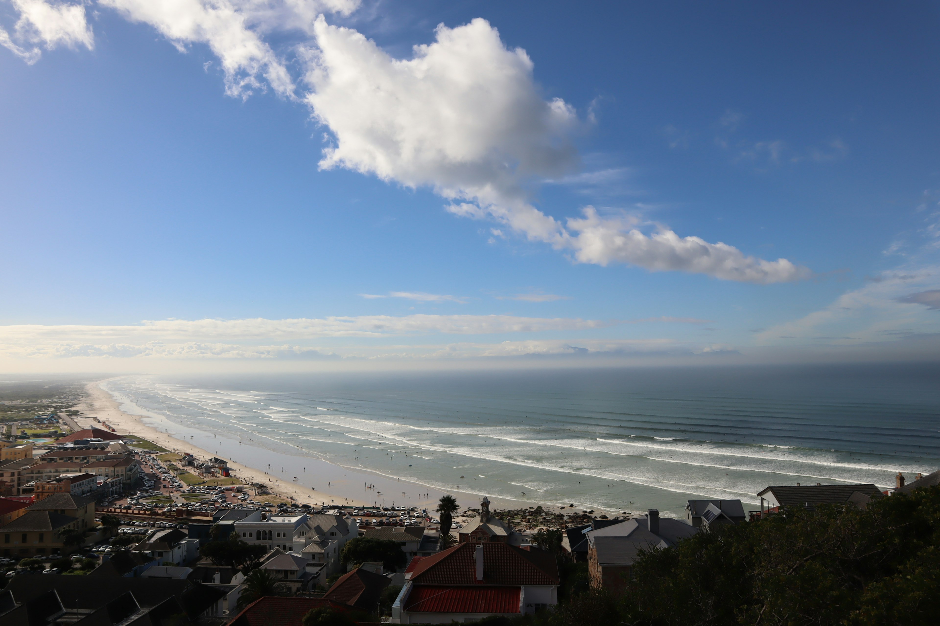 Scenic view of ocean waves and coastline under a blue sky with clouds