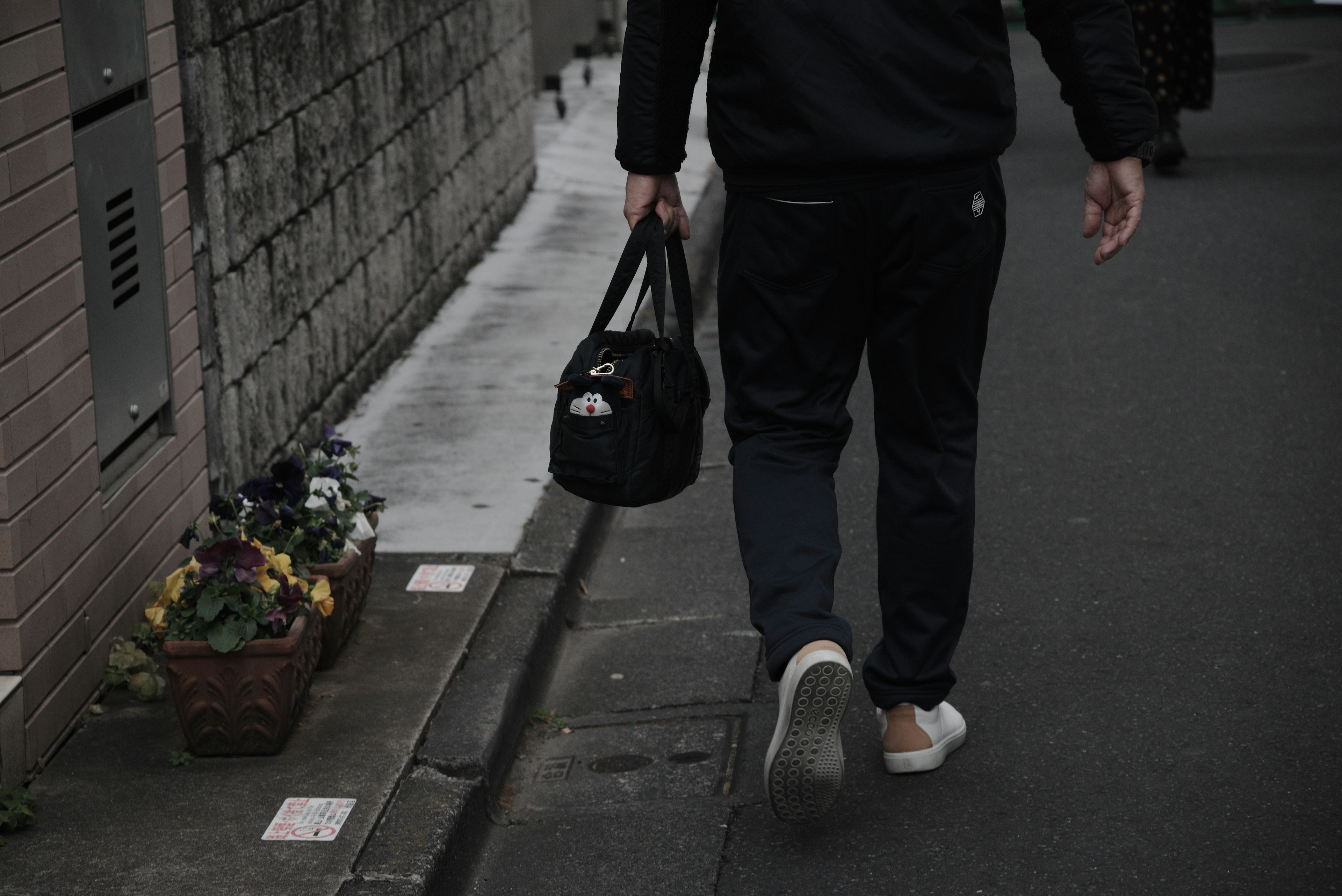 暗い通りを歩く男性と黒いバッグ