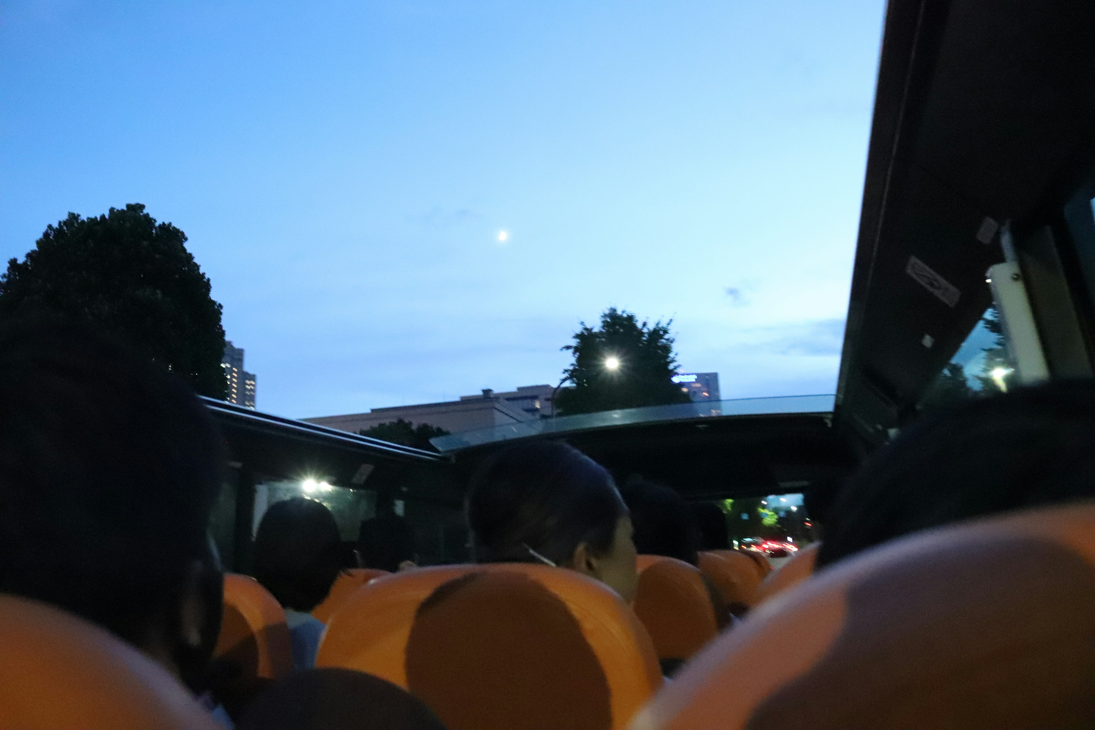 Vista interna di un autobus con sedili arancioni e cielo serale