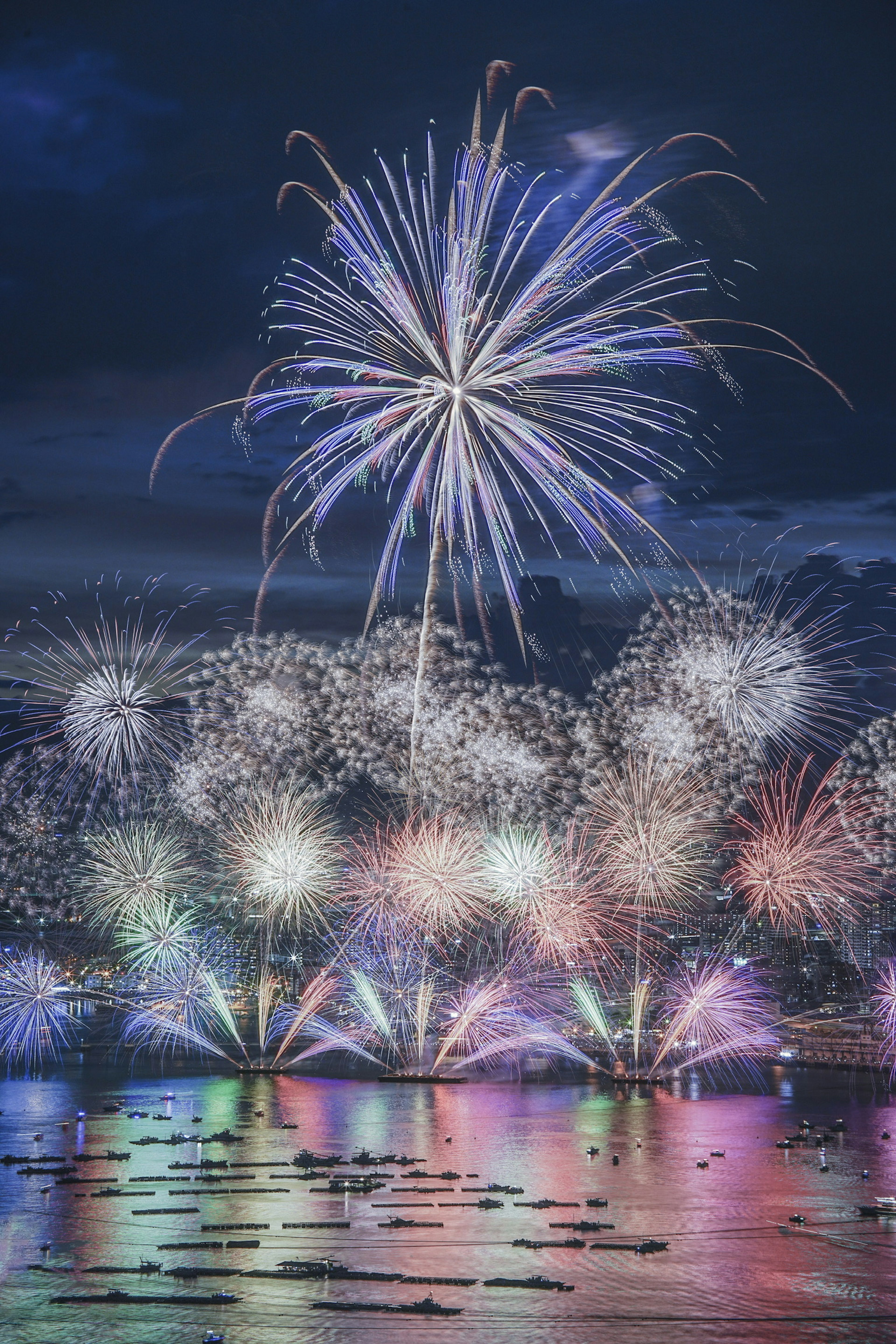 Des feux d'artifice colorés éclatant dans le ciel nocturne se reflétant sur la surface de l'eau