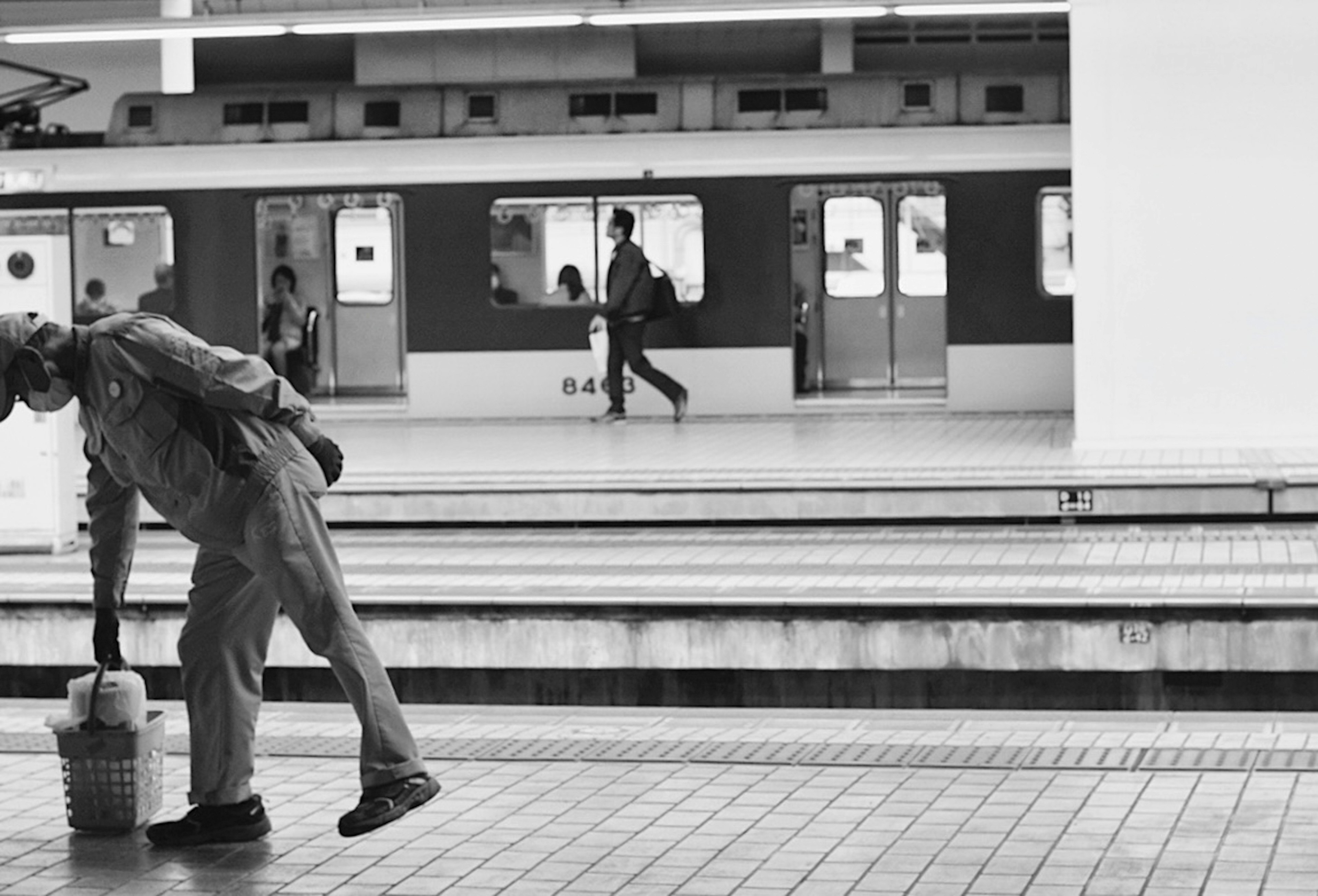 駅で掃除をする高齢者の男性と電車