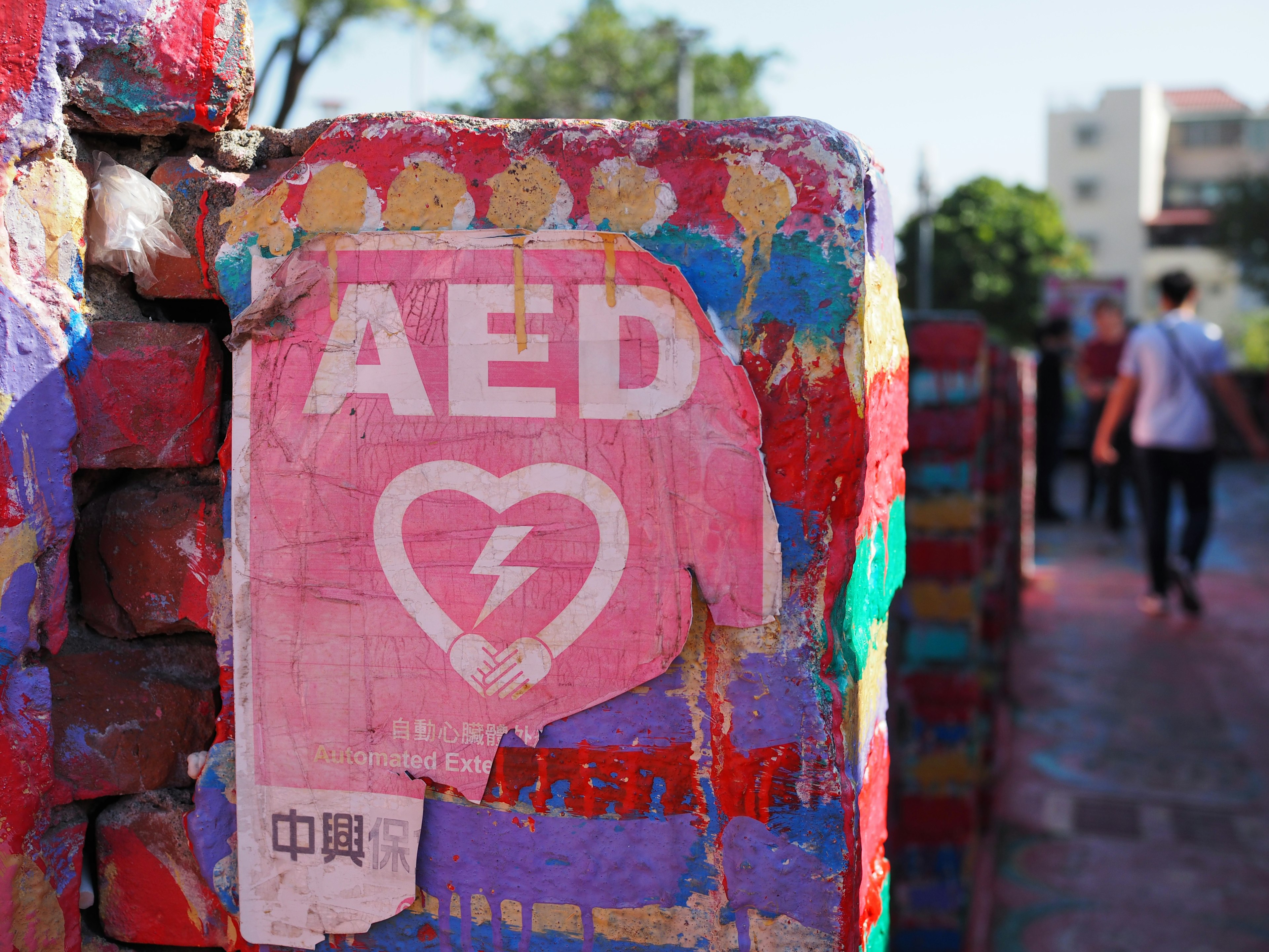 AED-Schild mit Herzsymbol an einer bunten Wand