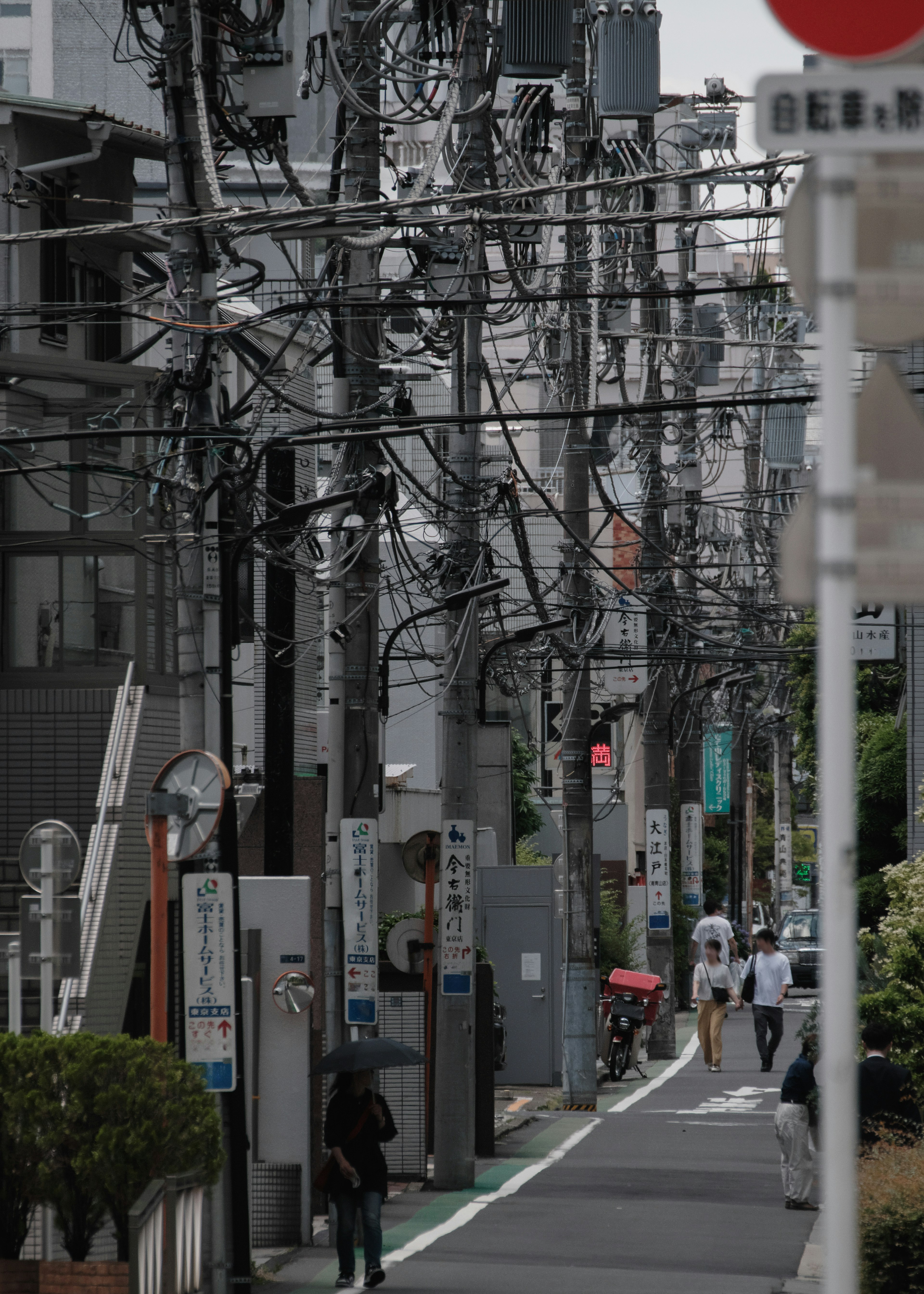 Urban street lined with utility poles and wires people walking and a bicycle present