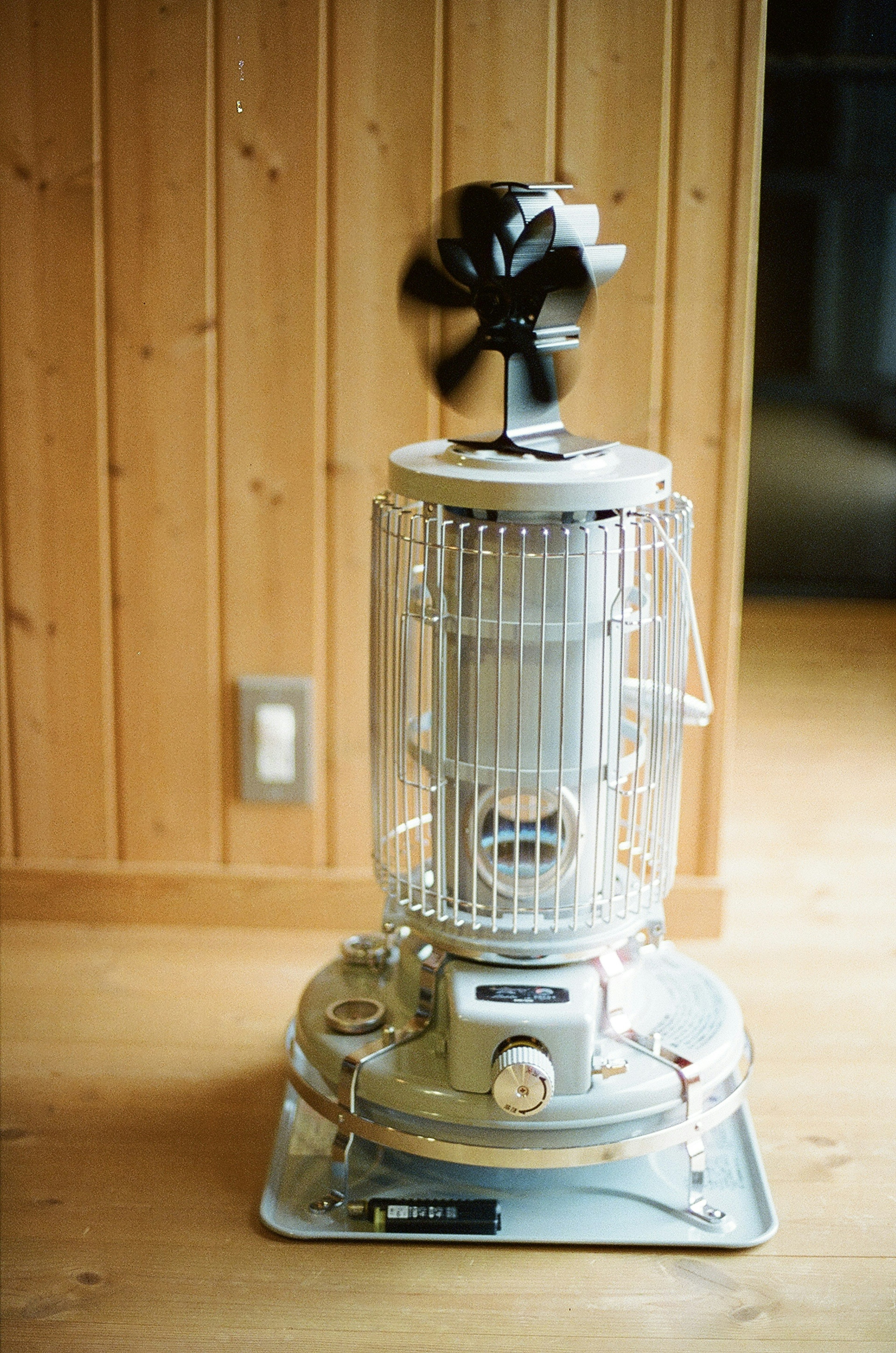 Metal fan heater placed in front of wooden wall