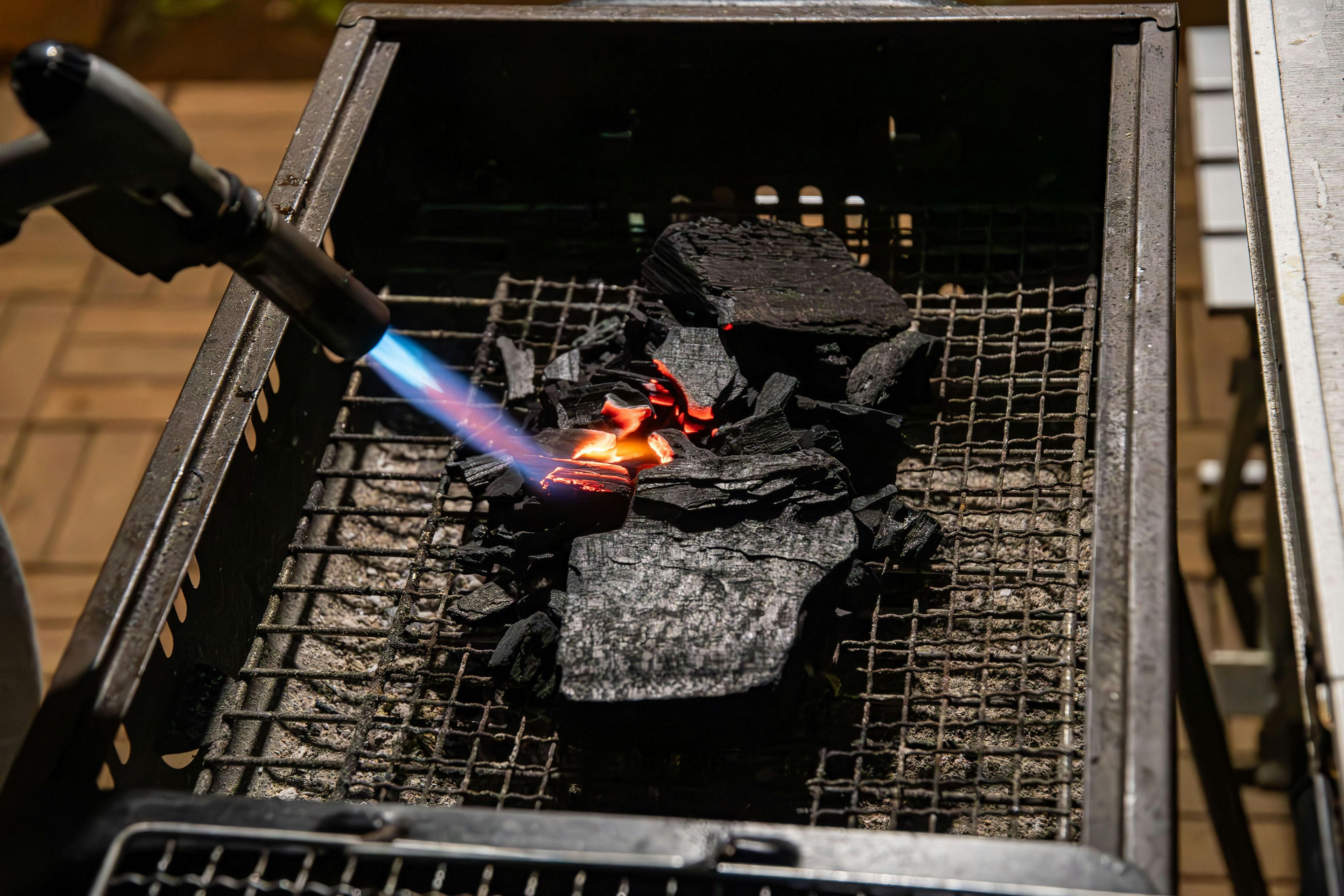 Utilisation d'un chalumeau pour allumer du charbon dans un grill