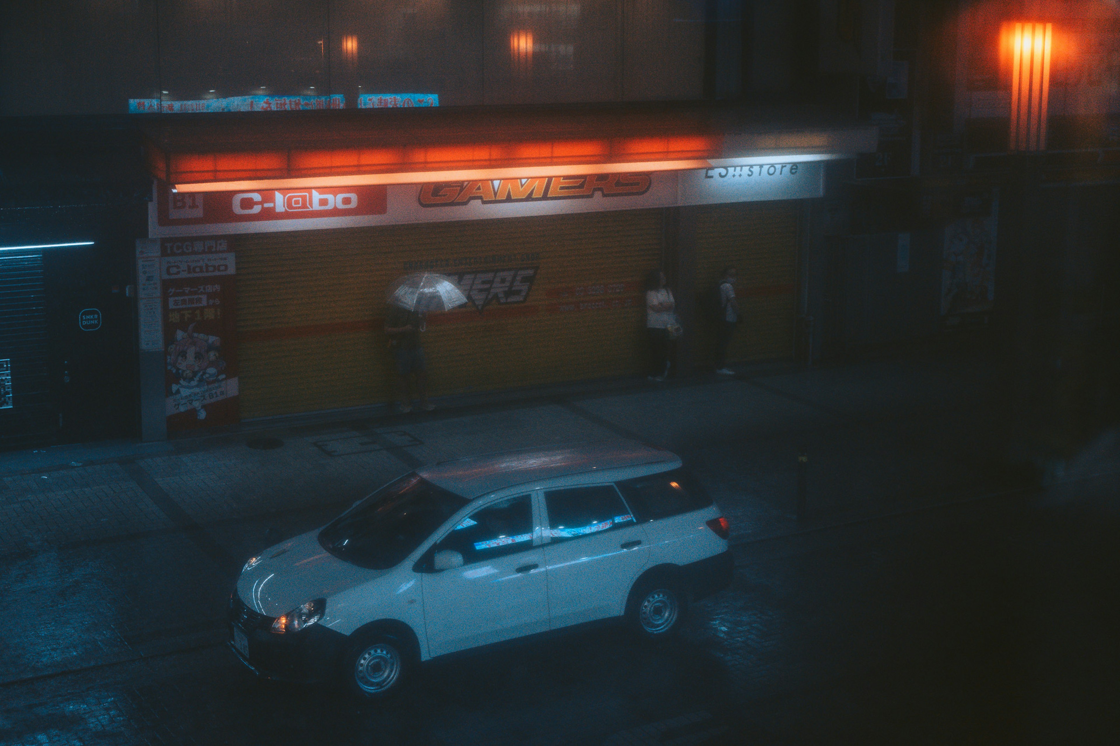 Night street scene with a white SUV and cafe exterior in the rain