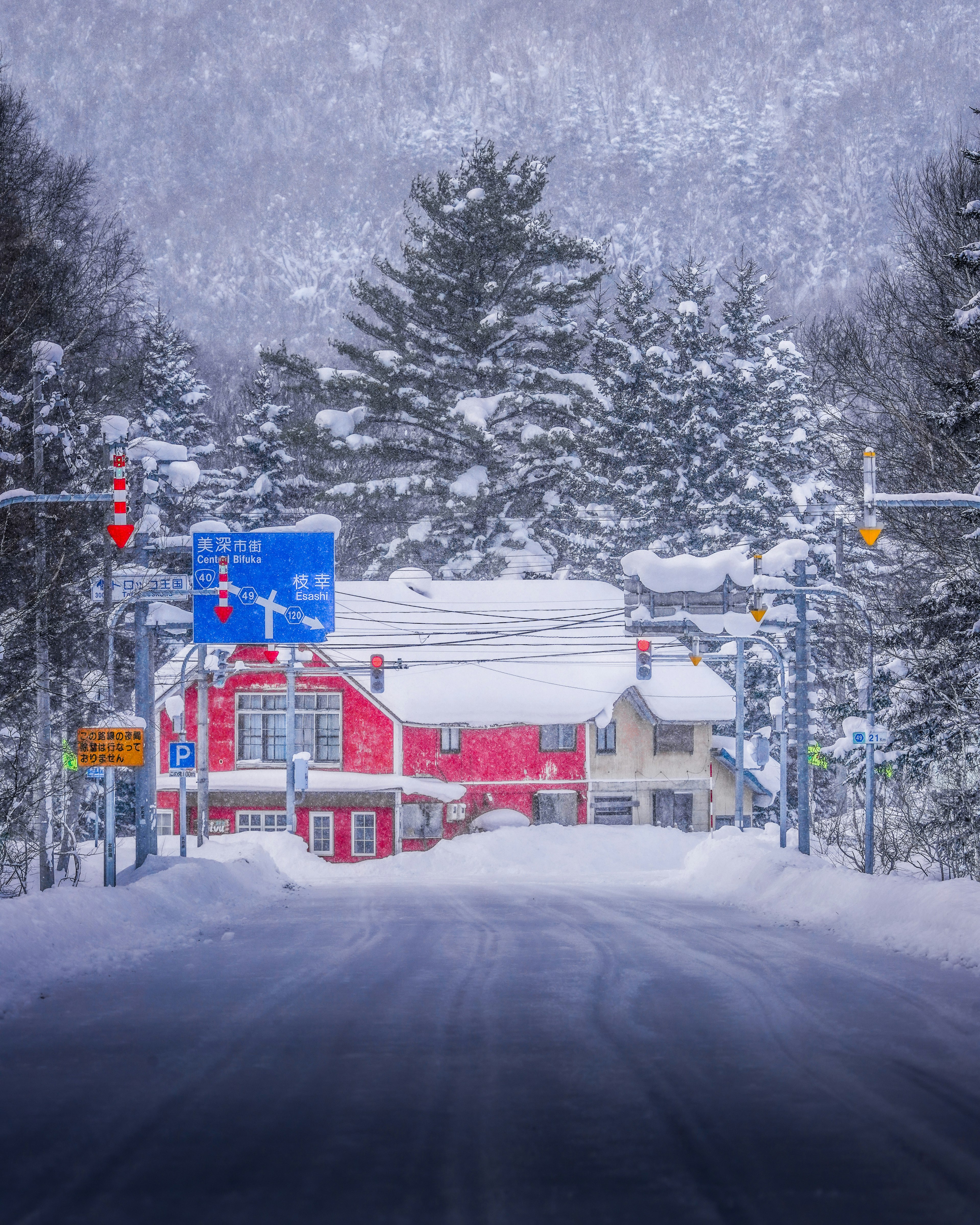 Schneebedeckte Straße mit einem roten Gebäude im Hintergrund