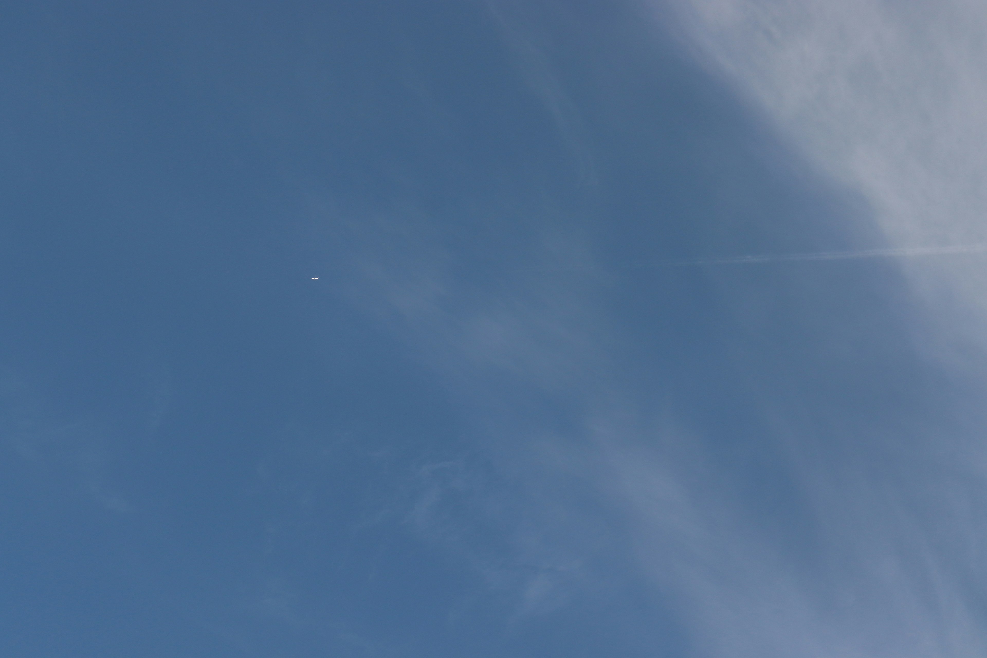 Un cielo azul brillante con un pequeño punto blanco y nubes tenues