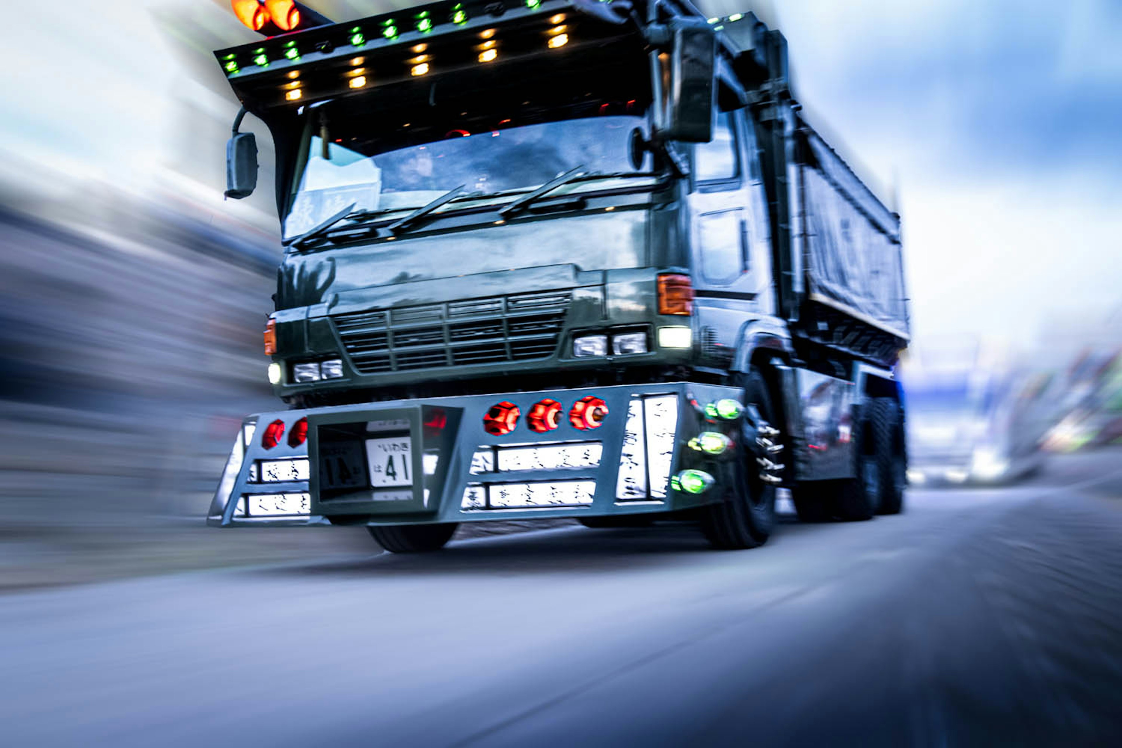 A dynamic black dump truck speeding down the road with colorful lights adorning the front