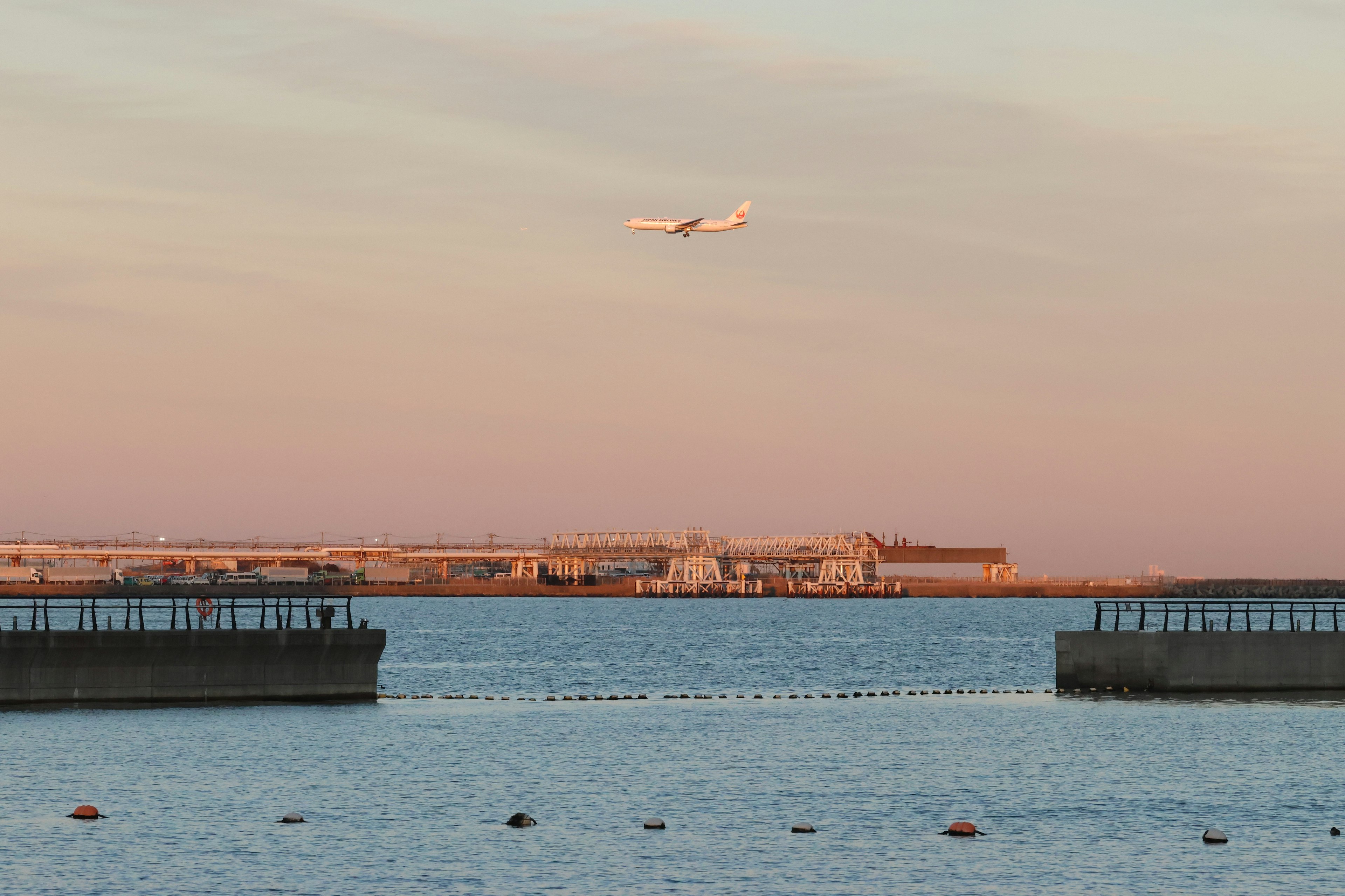 夕焼け空に浮かぶ飛行機と港の風景