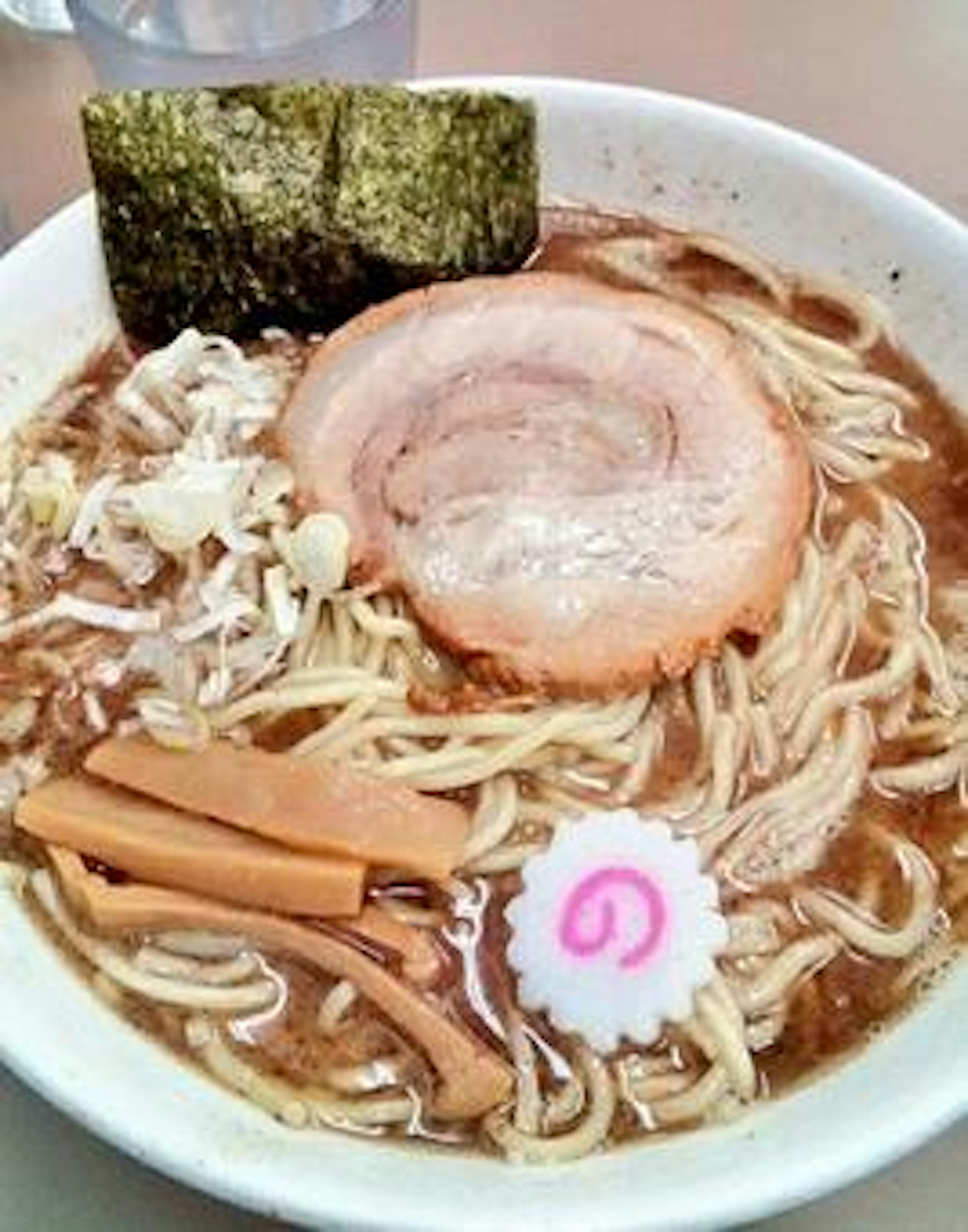 Un tazón de ramen con cerdo en rodajas, alga, brotes de bambú, narutomaki y brotes de soja